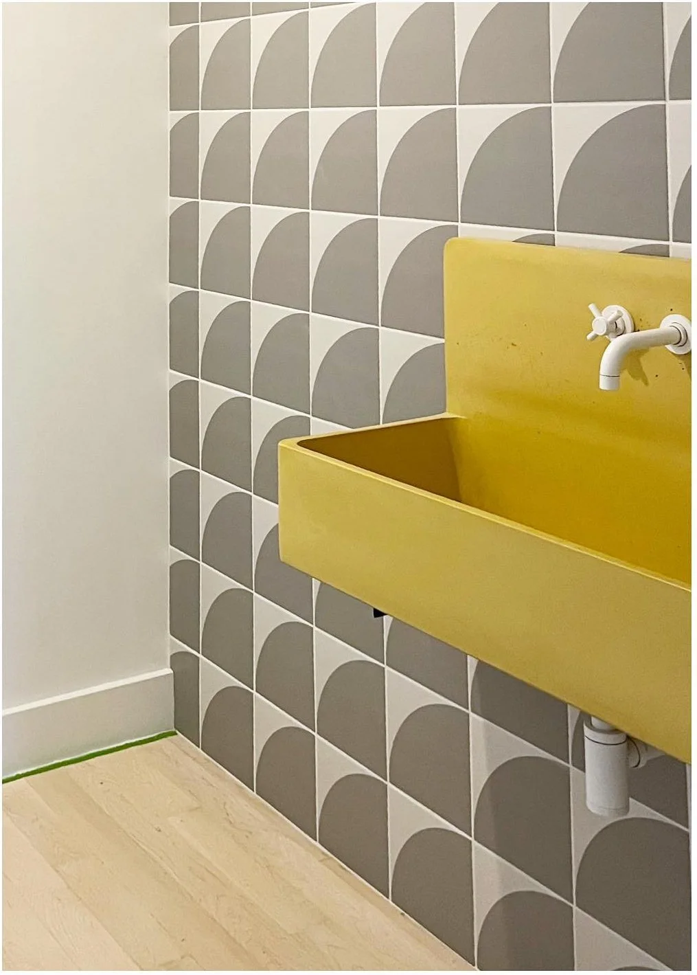 Yellow double basin beneath slim white wall-mounted taps