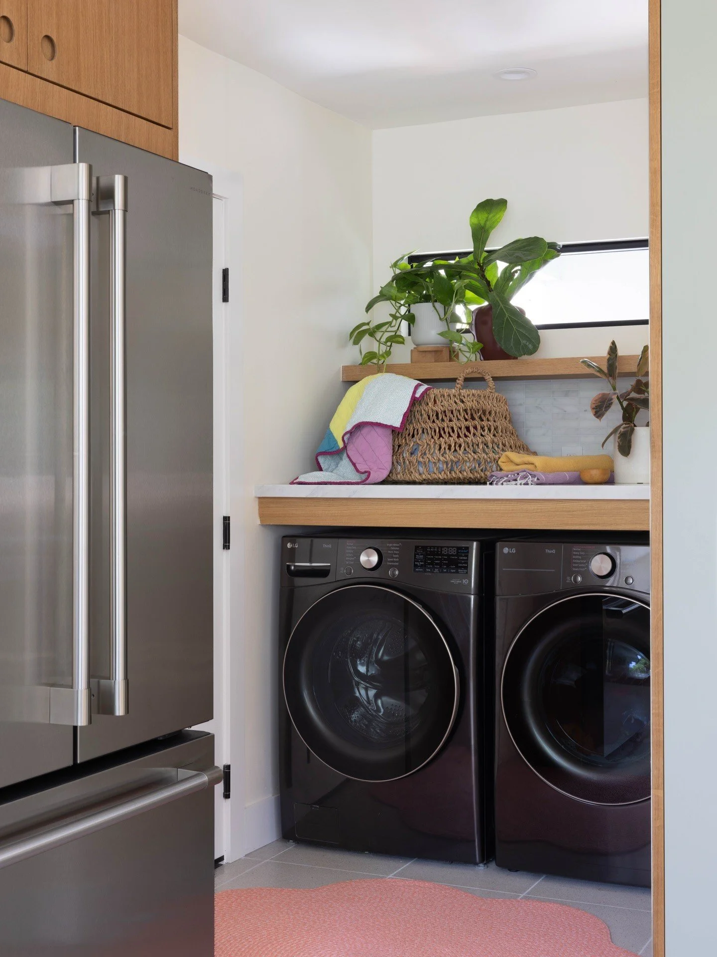 Laundry nook with black appliances and pale green storage