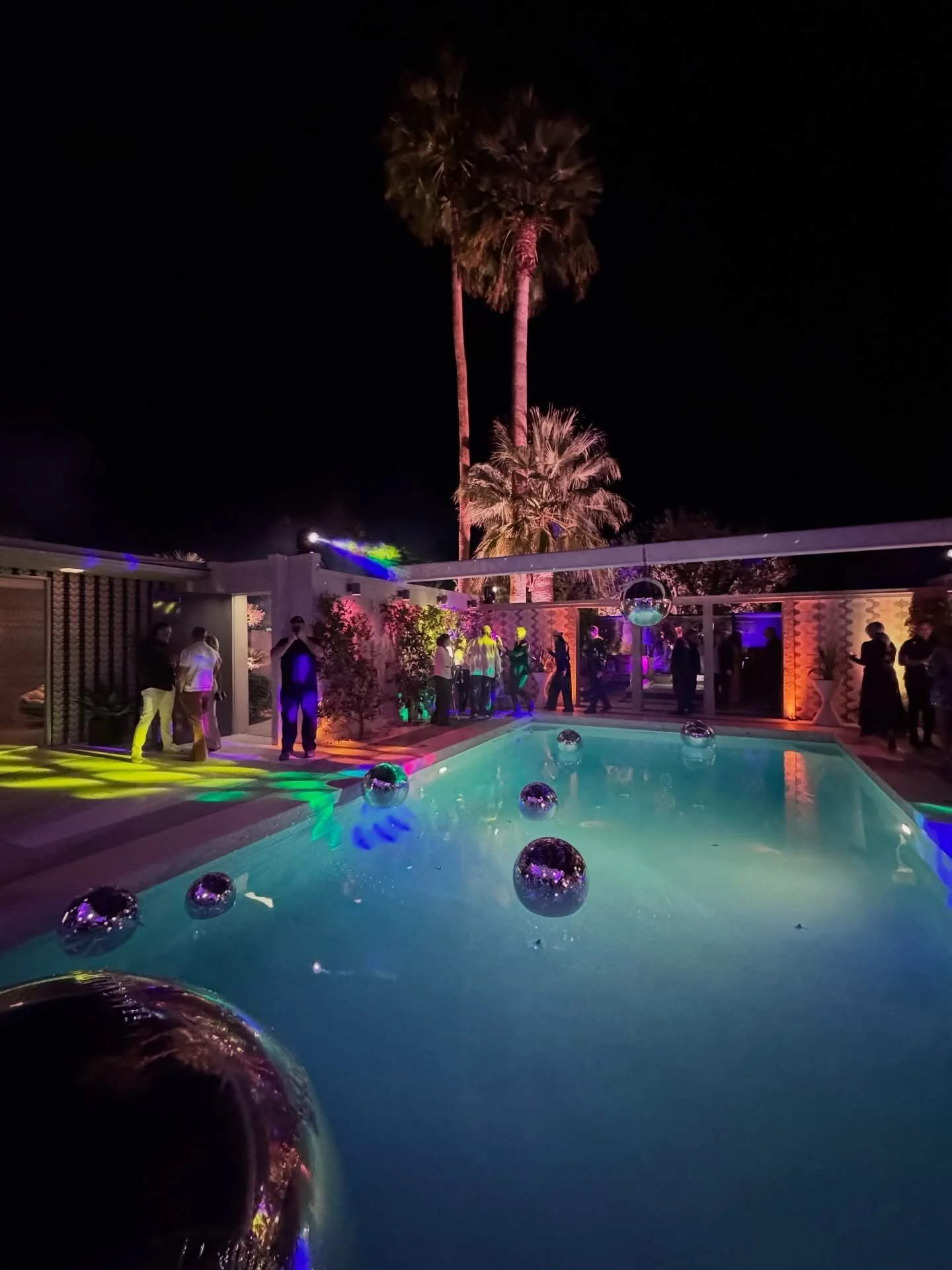Illuminated courtyard pool with reflective spheres and a tall palm