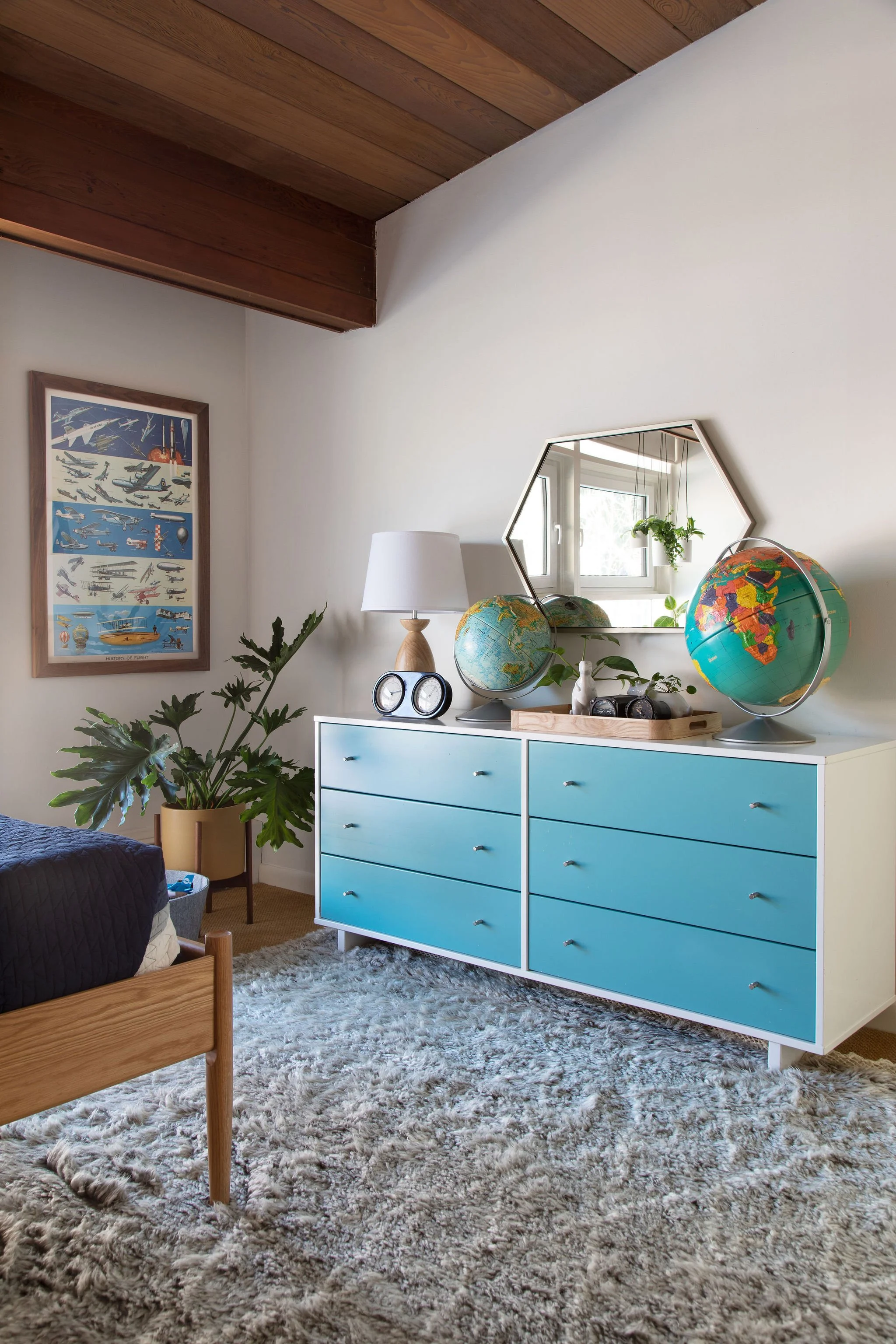 Bedroom with a turquoise dresser, globe, and wood ceiling.