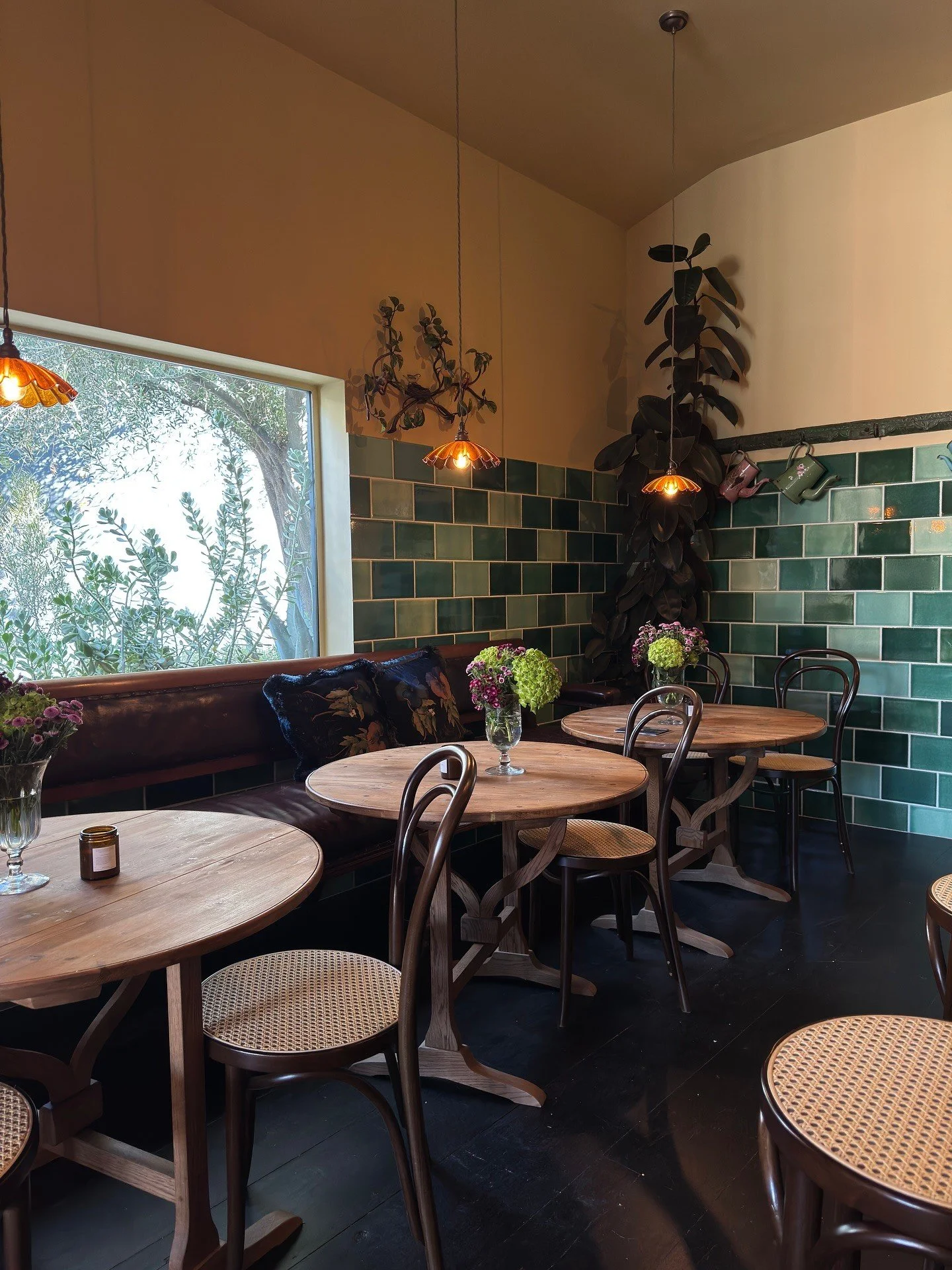 Cafe seating beside green tile and a mustard painted wall