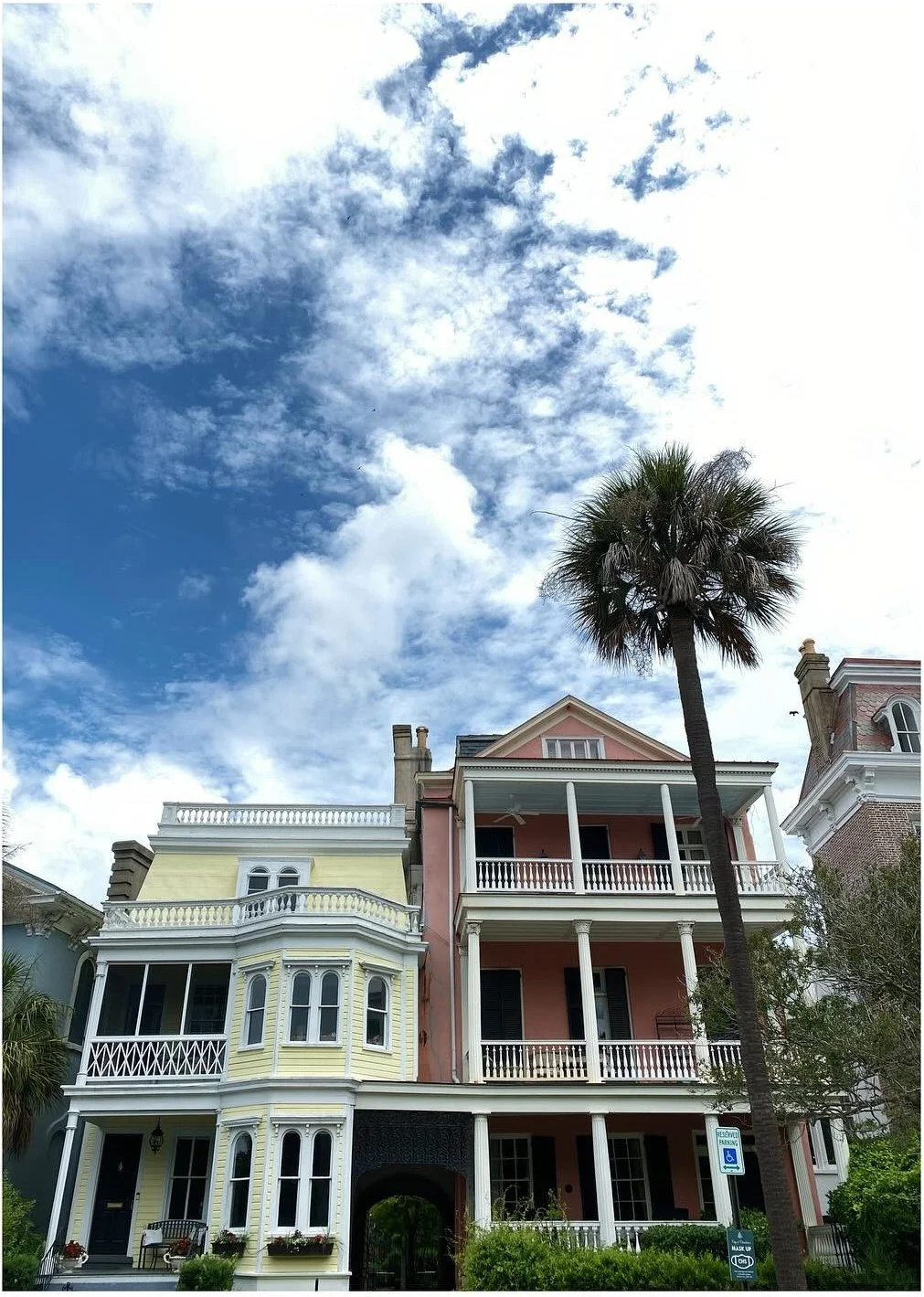 Historic pastel houses with deep porches and a tall palm