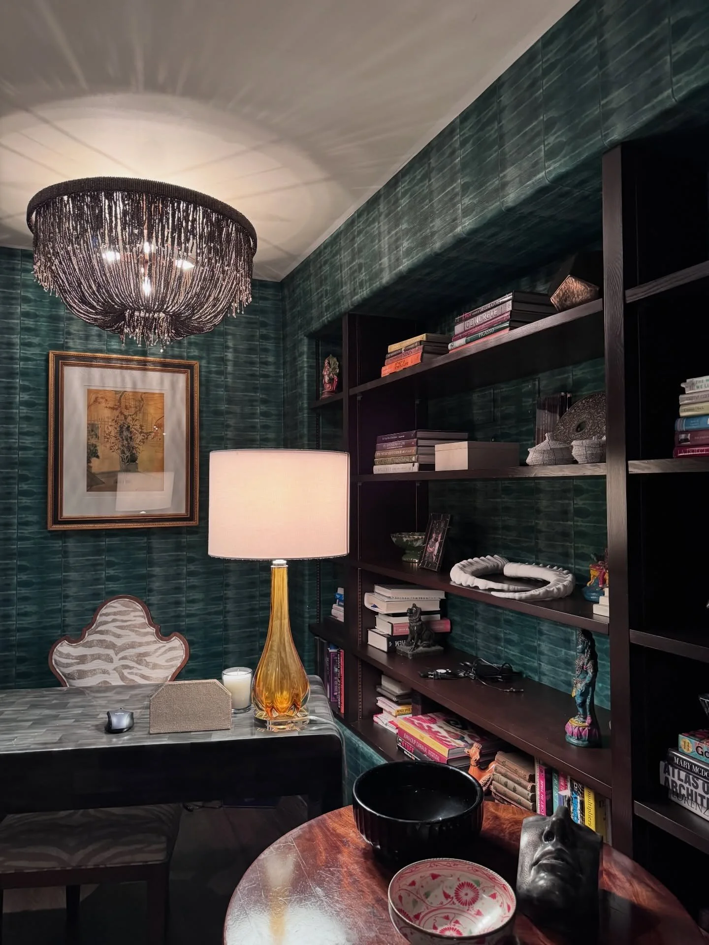 Green tiled study with bookshelves and a brass table lamp