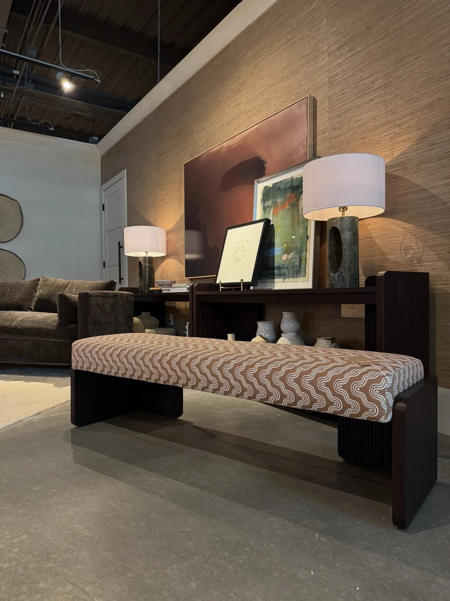 Upholstered bench and dark wood console beneath framed art