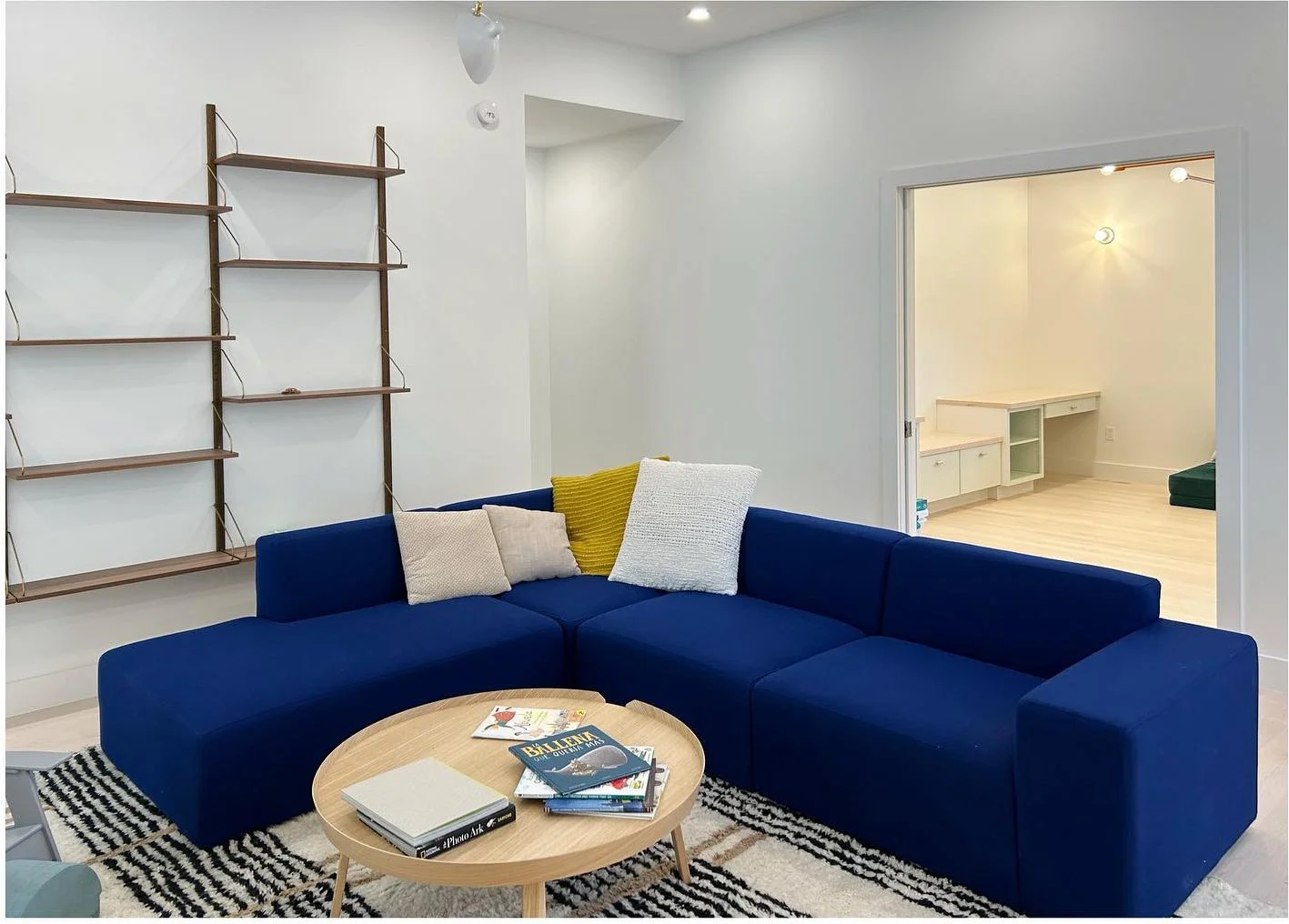 Blue sectional beneath wall-mounted shelves and a wide interior opening