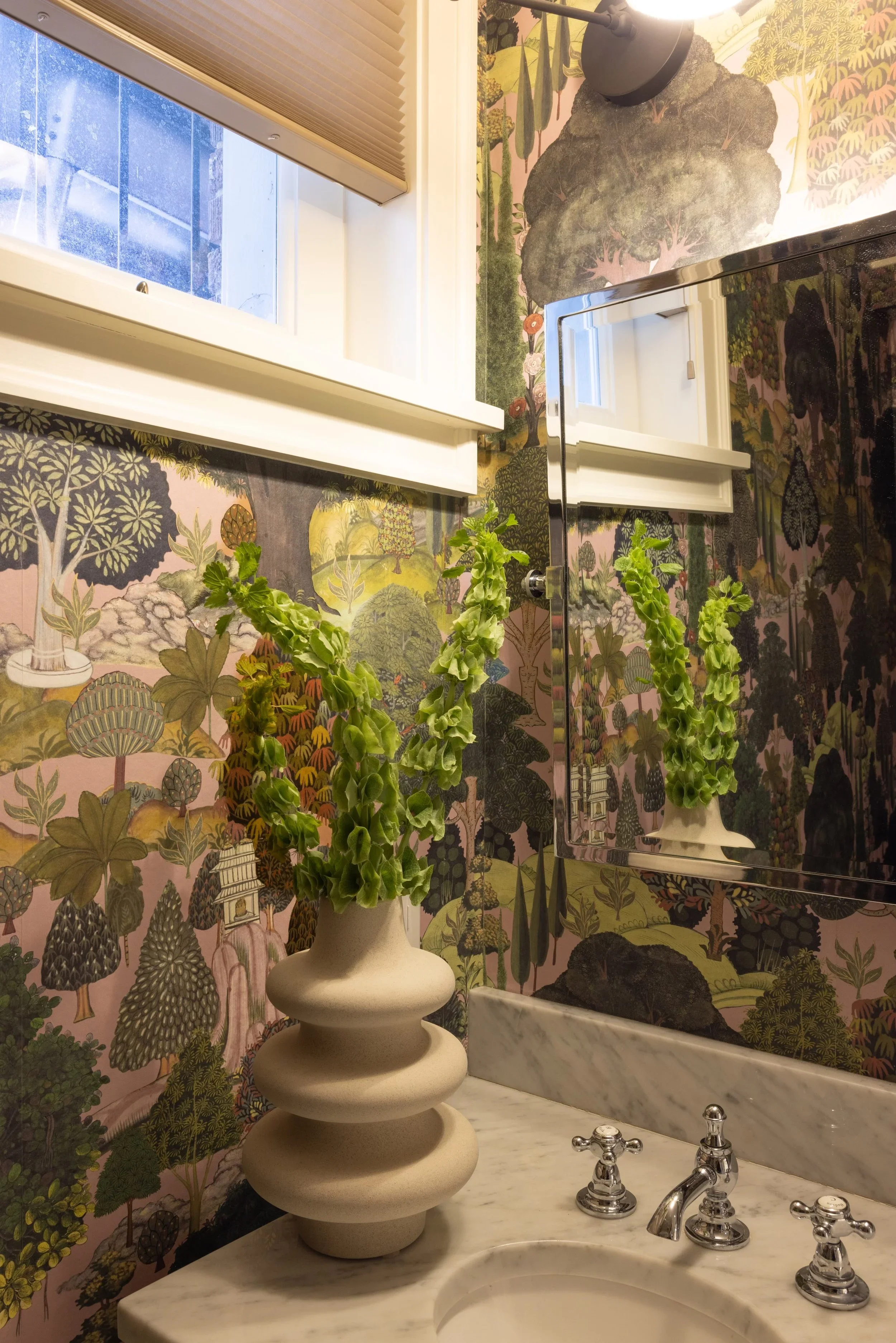 Floral wallpaper and potted plants beside a bathroom window.