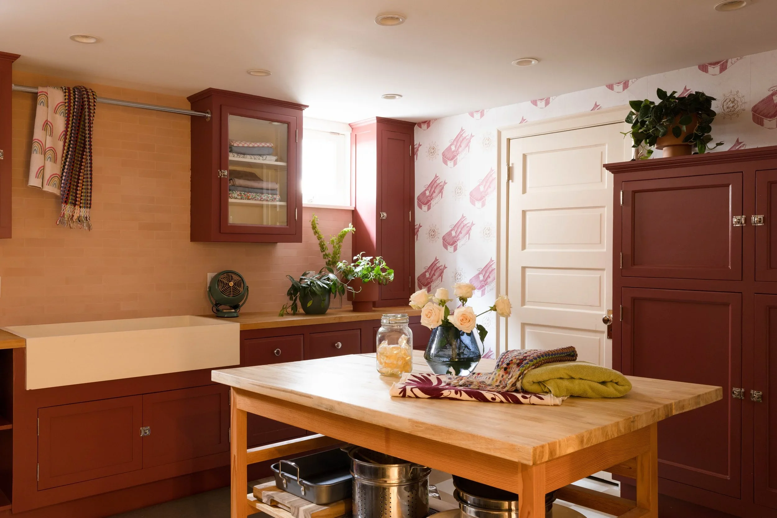 Kitchen with burgundy cabinets, a farmhouse sink, and a wood worktable.