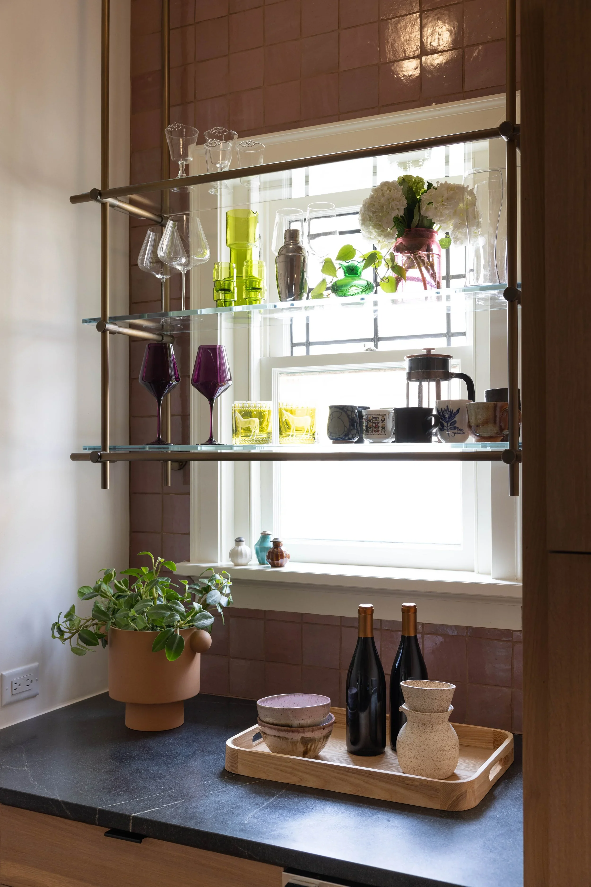 Brass-framed glass shelves displaying plants and glassware.
