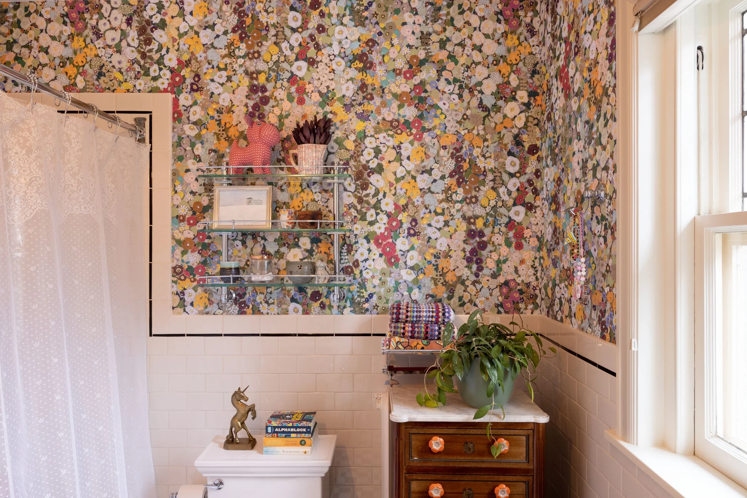 Powder room with dense floral wallpaper and a small wood cabinet.