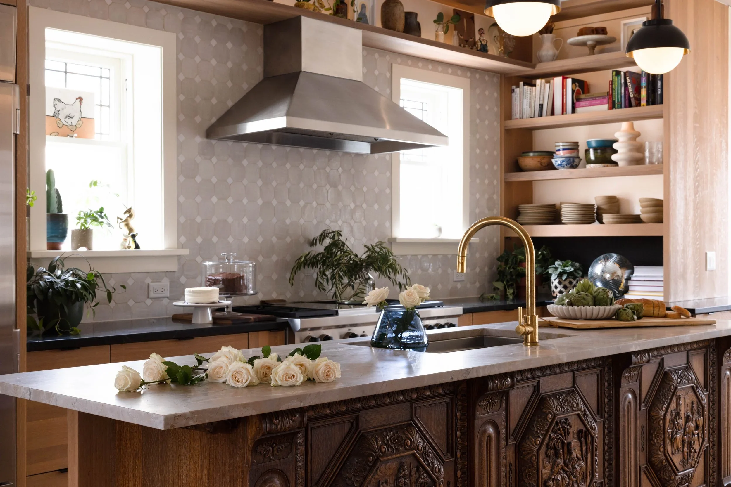 Carved wood kitchen island beneath a stainless steel range hood.