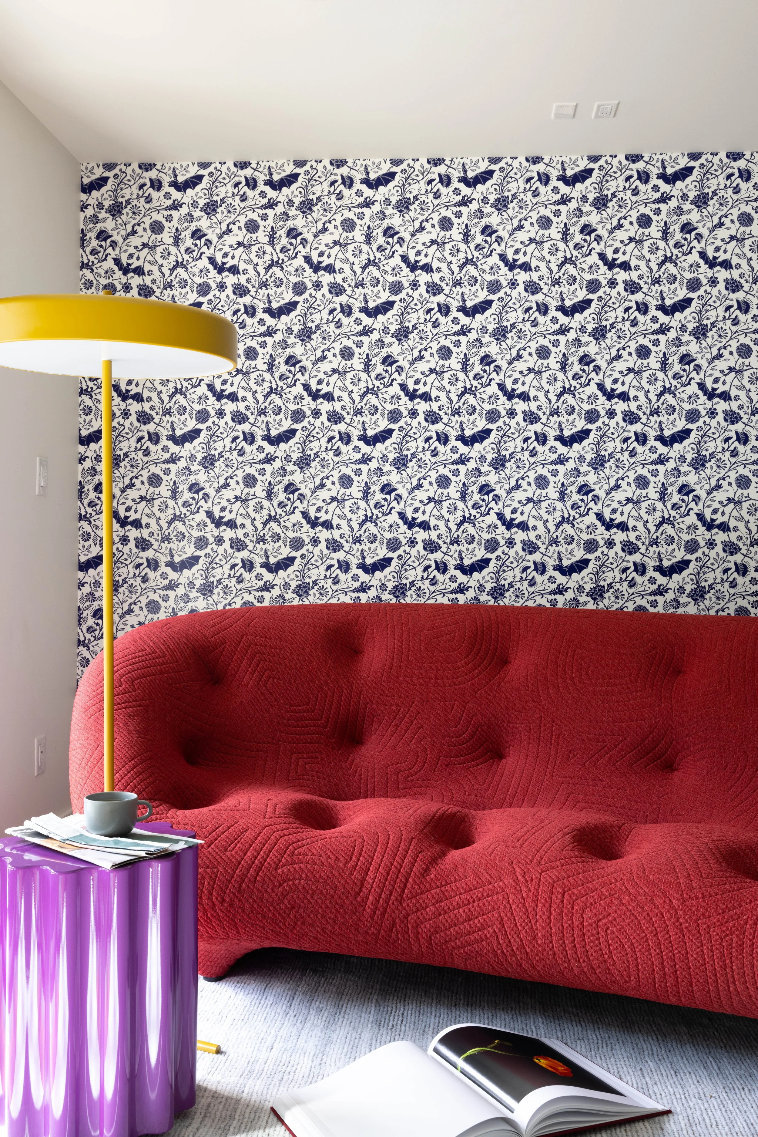 Media room with a red tufted sofa and patterned wallpaper.