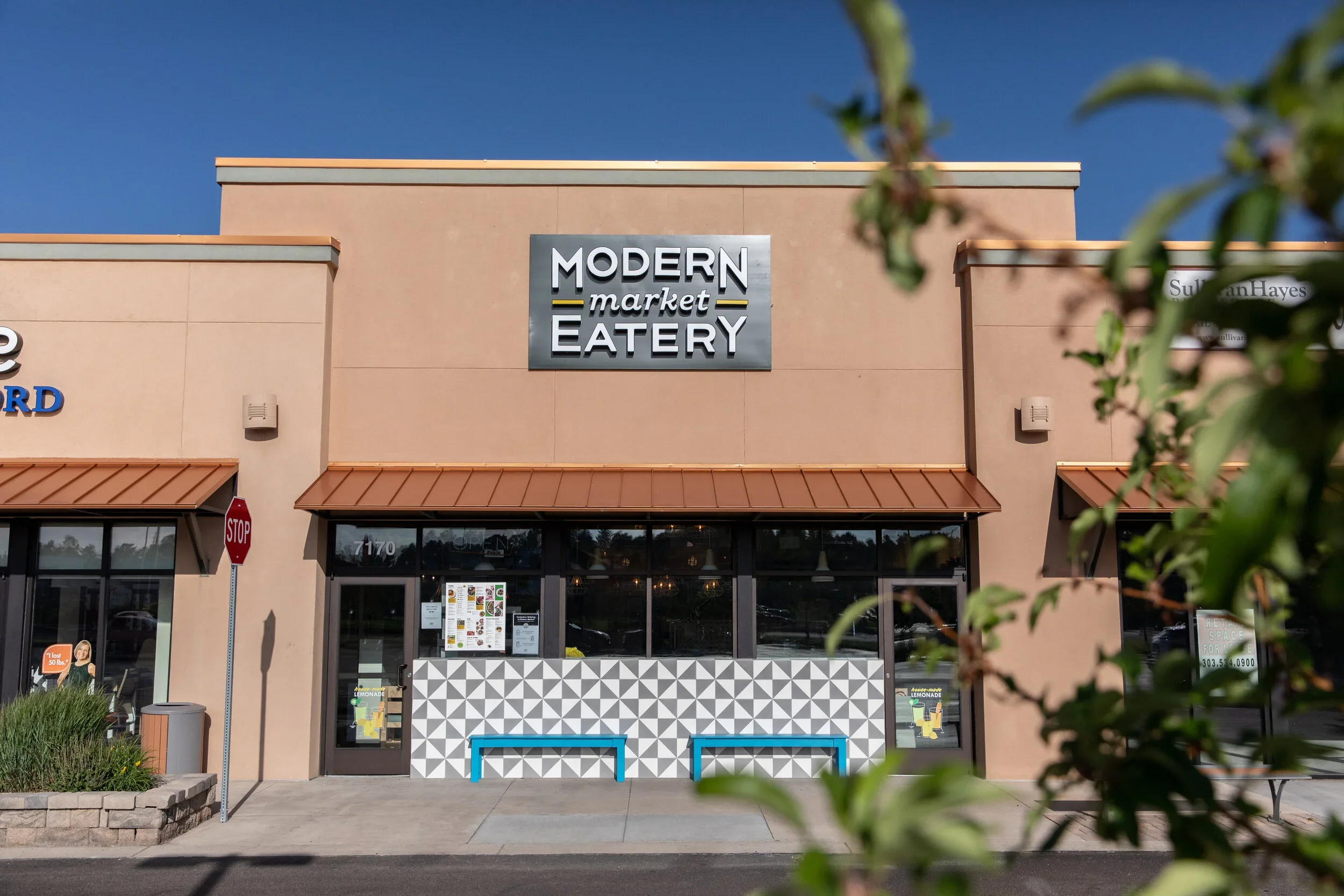 Modern Market Eatery storefront with peach facade, restaurant sign, black-framed entrance, and climbing greenery. Photography by Nathan Warmes