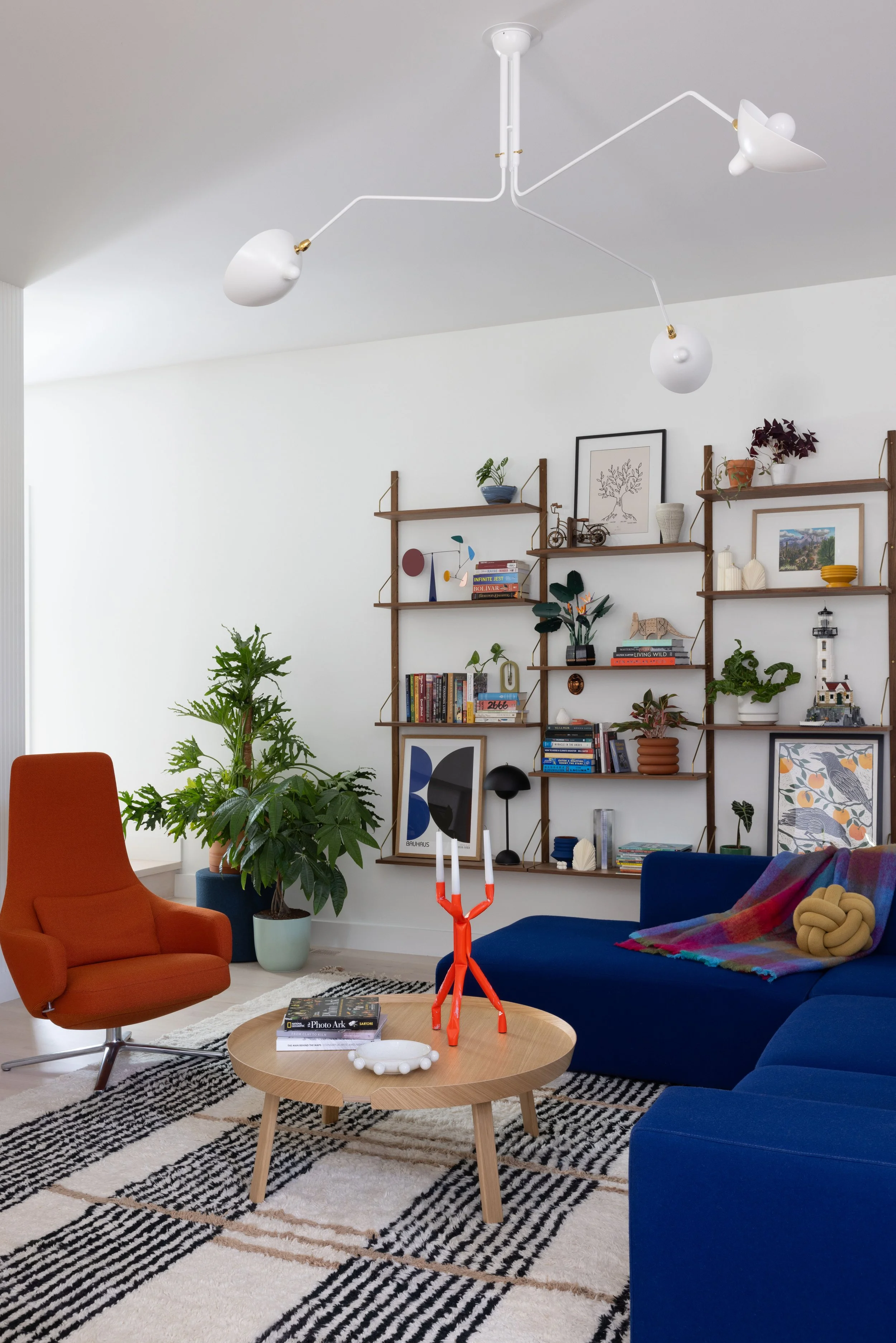  Bright as Yellow ↗  A blue sectional, orange chair, and layered patterned rug.