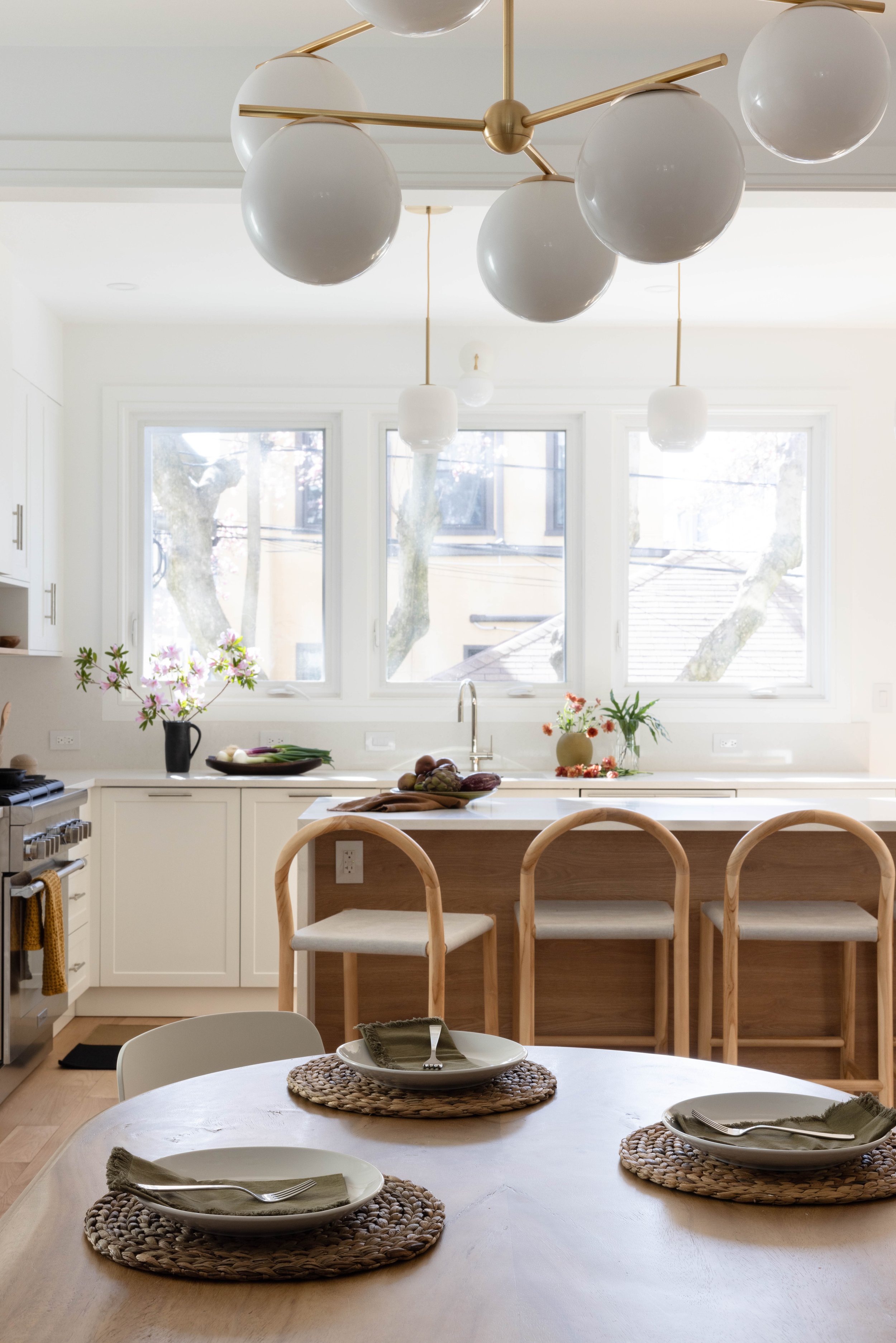  Fade Into You ↗  A round wood dining table beneath clustered globe pendants.