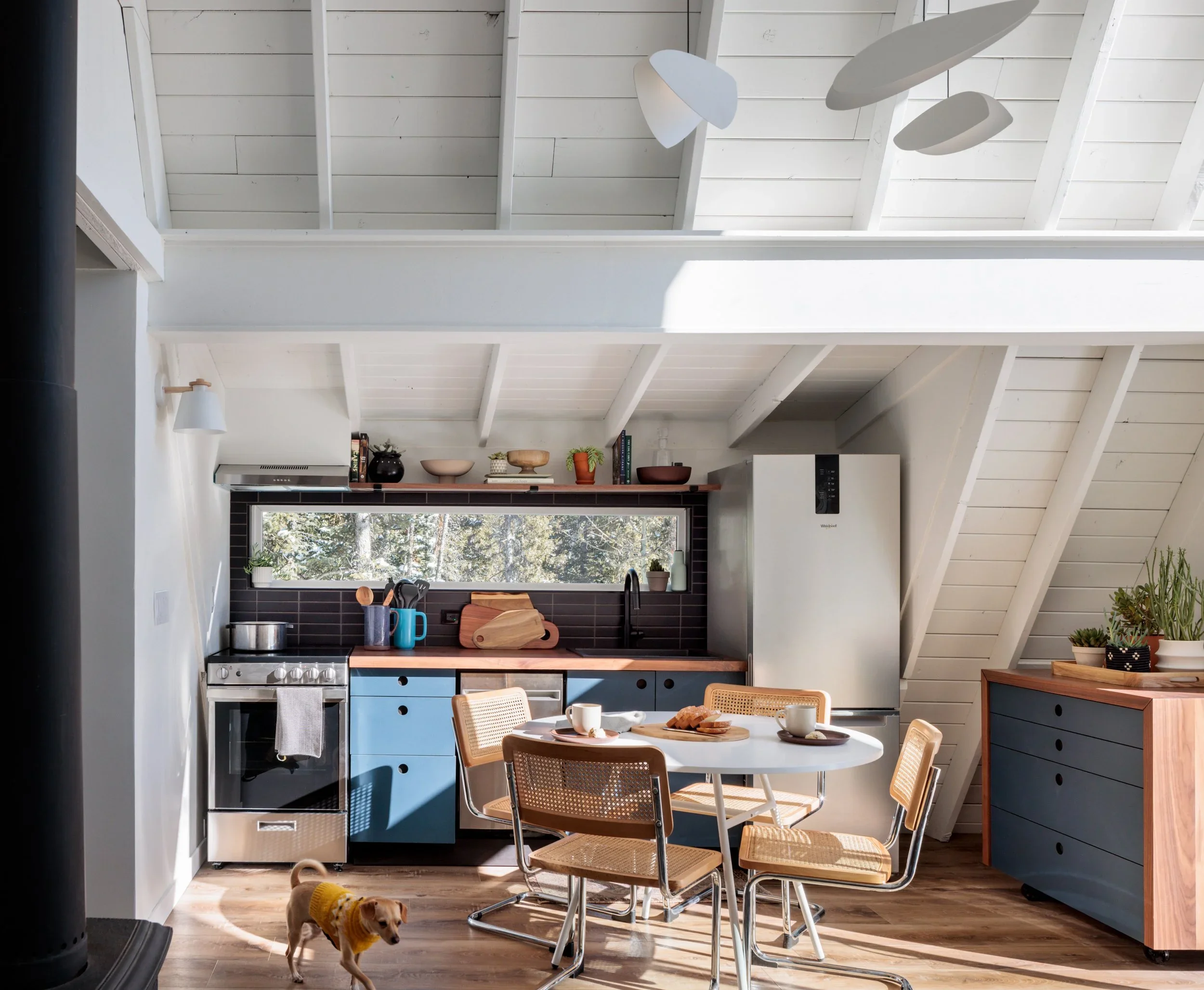  Camp Altezza A-Frame ↗  Blue cabinetry beneath the original A-frame beams.