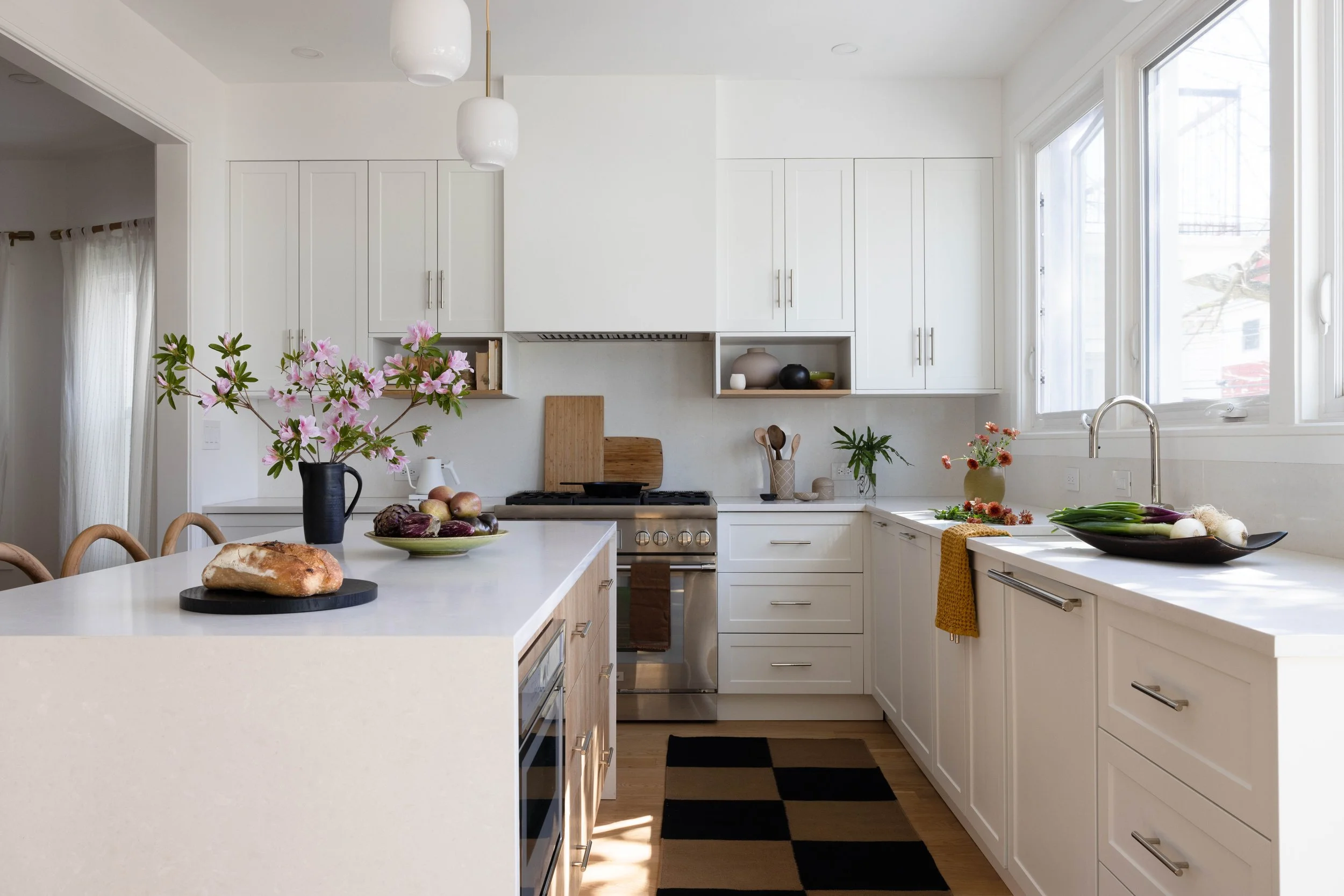 White kitchen island and pale wood cabinetry beneath a window.
