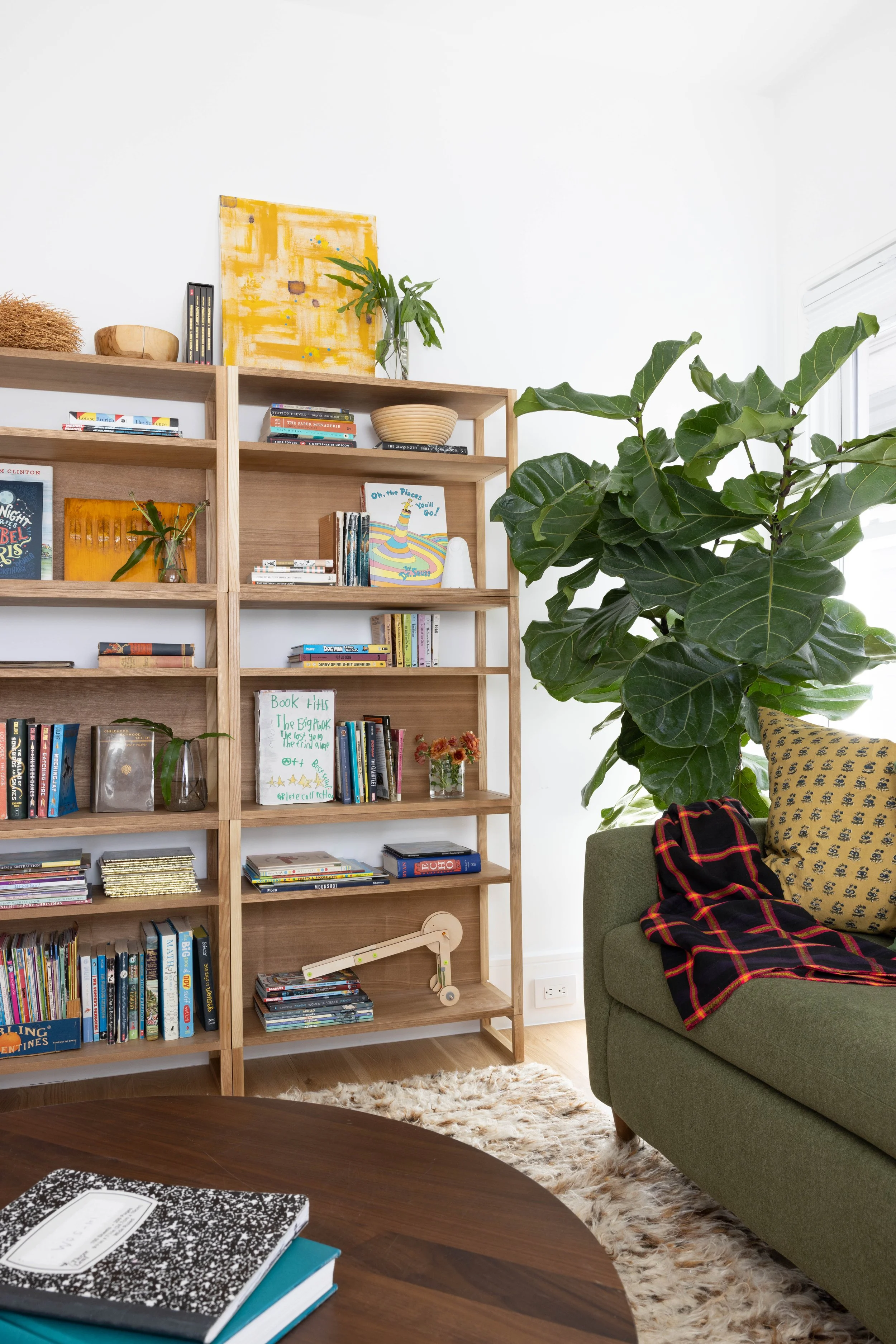 Library with open wood shelving and a green upholstered seat.