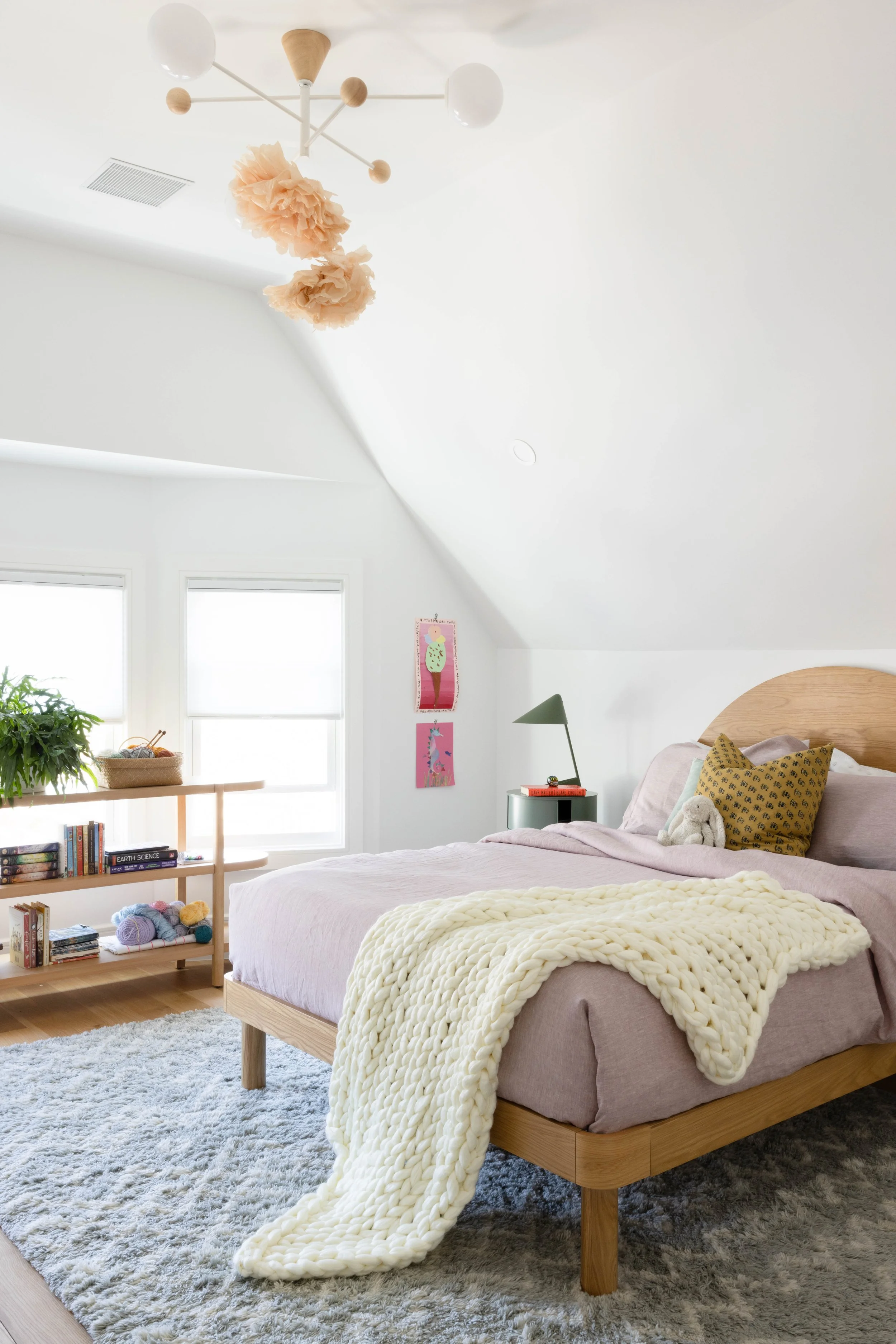 Bedroom with a curved wood headboard and pastel bedding.