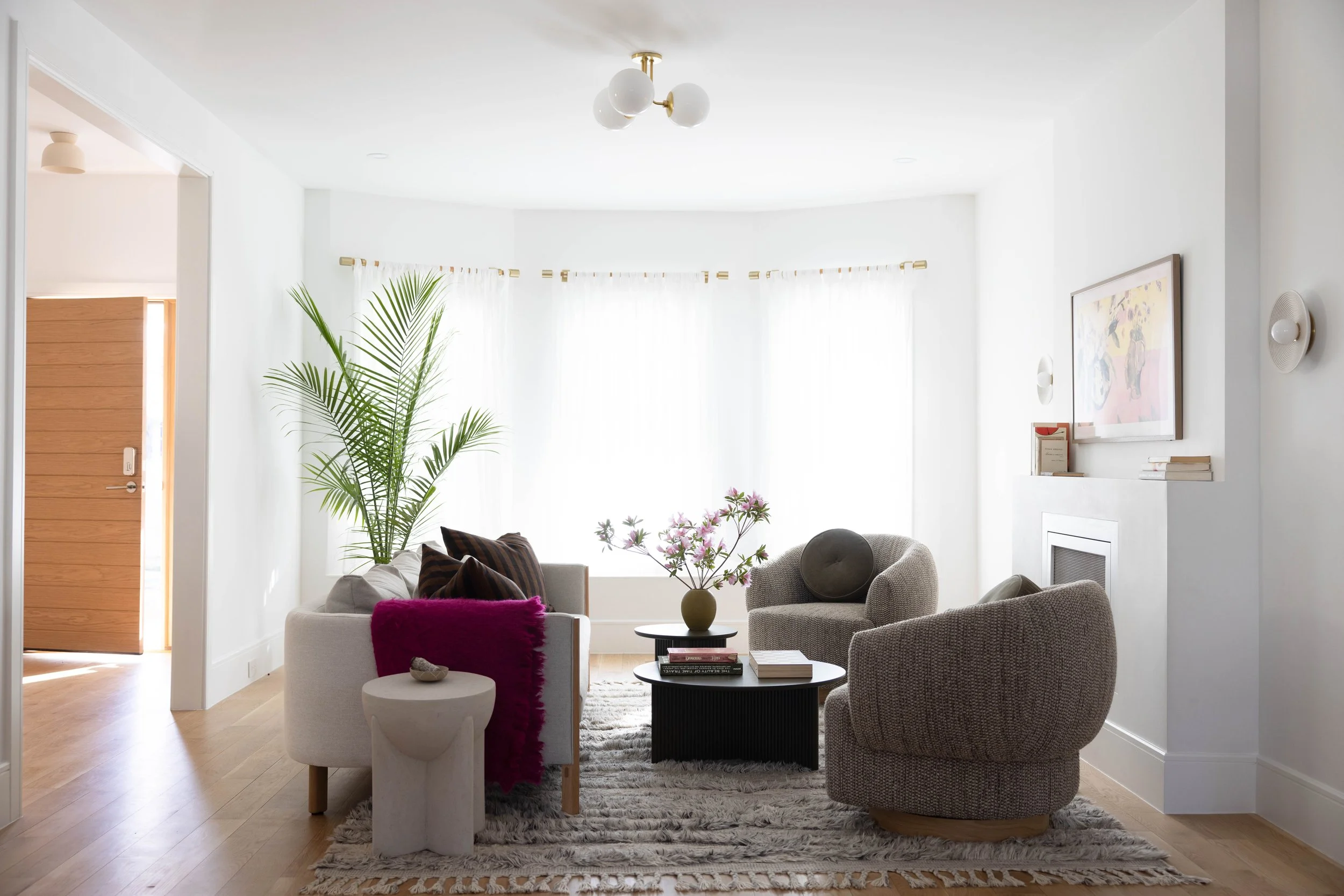 Parlor with textured swivel chairs, magenta seating, and a gray rug.