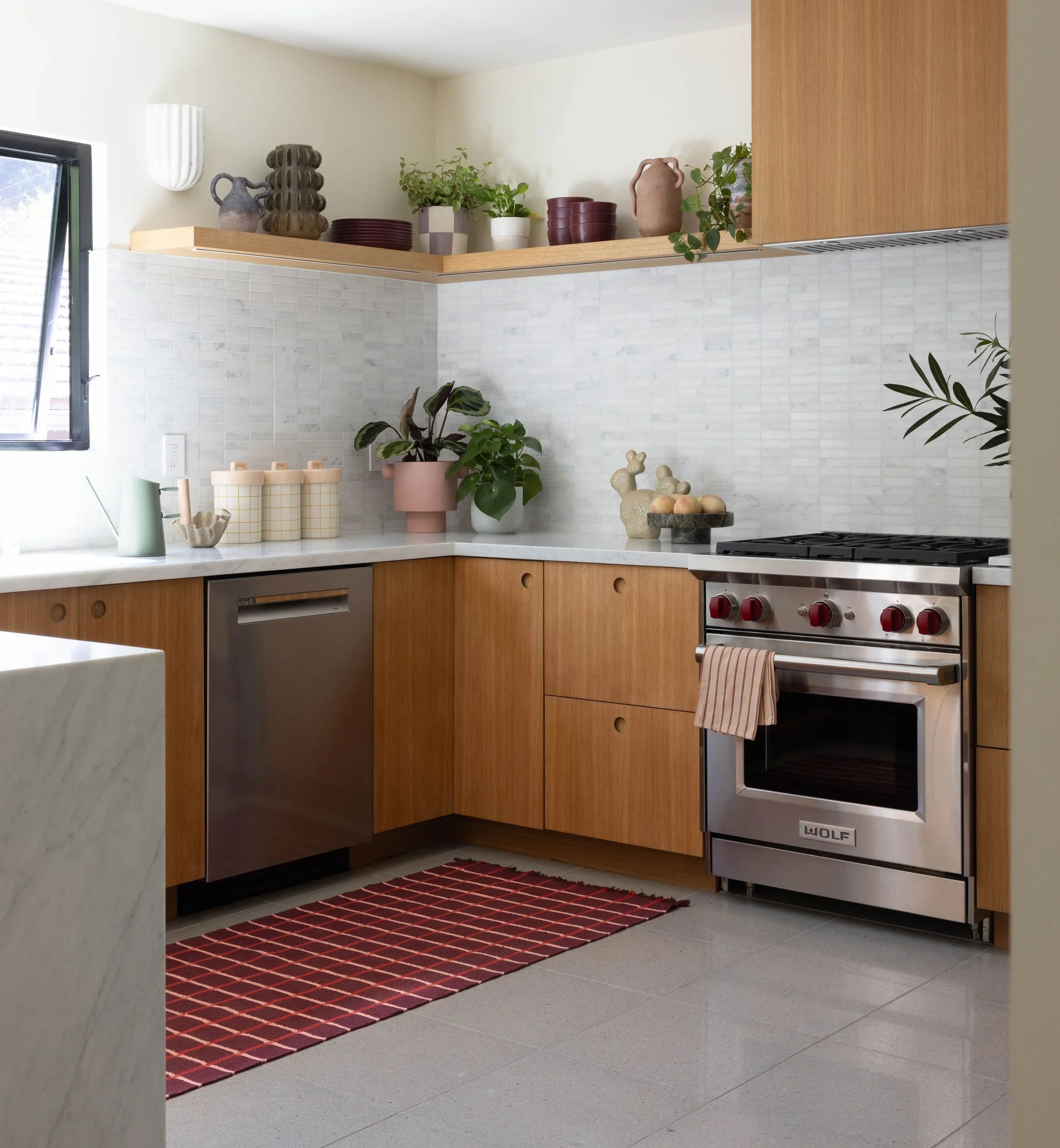 Kitchen with oak cabinets, marble backsplash, and open shelves.
