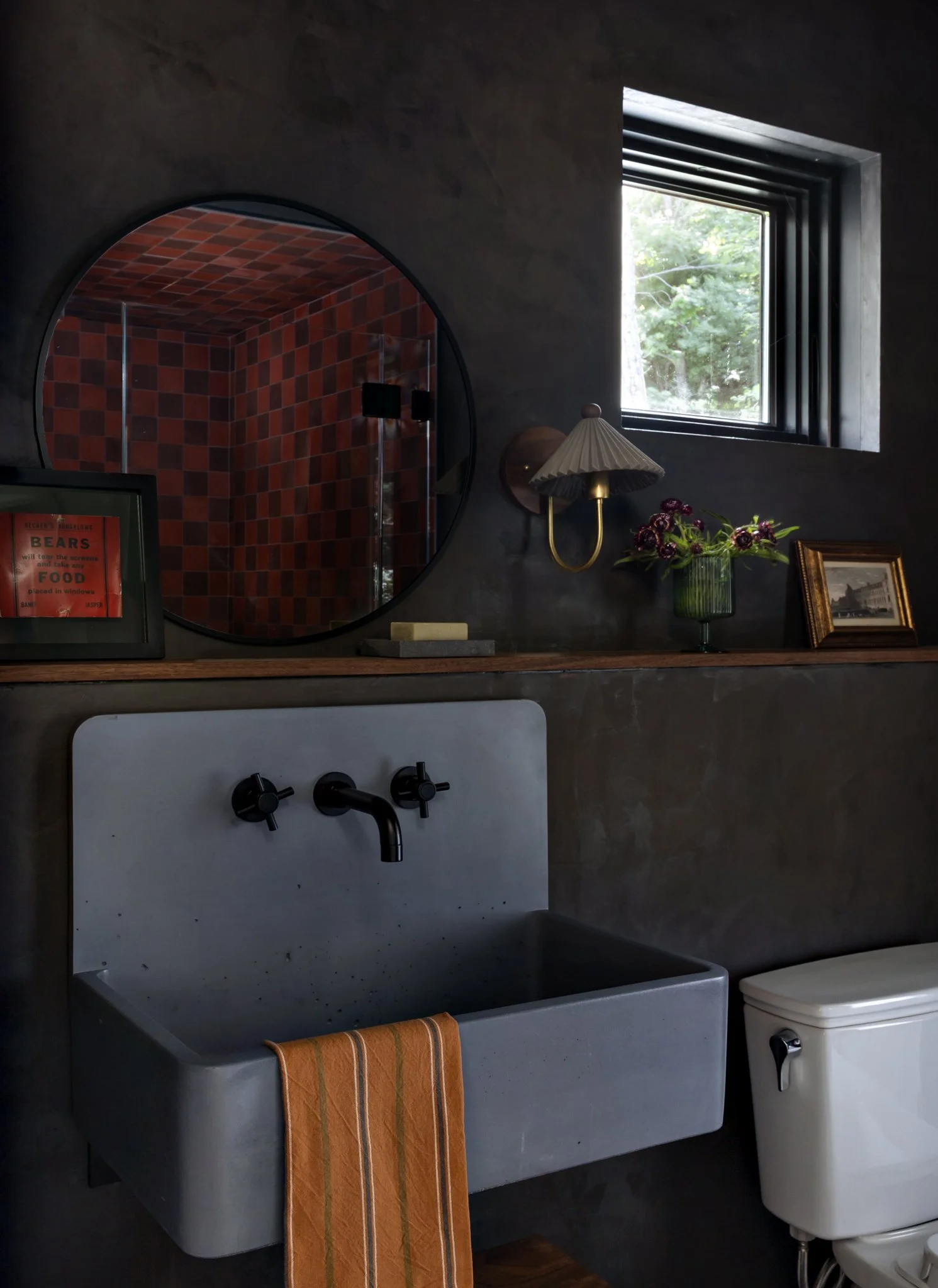 White wall-mounted sink beneath an arched red mirror.