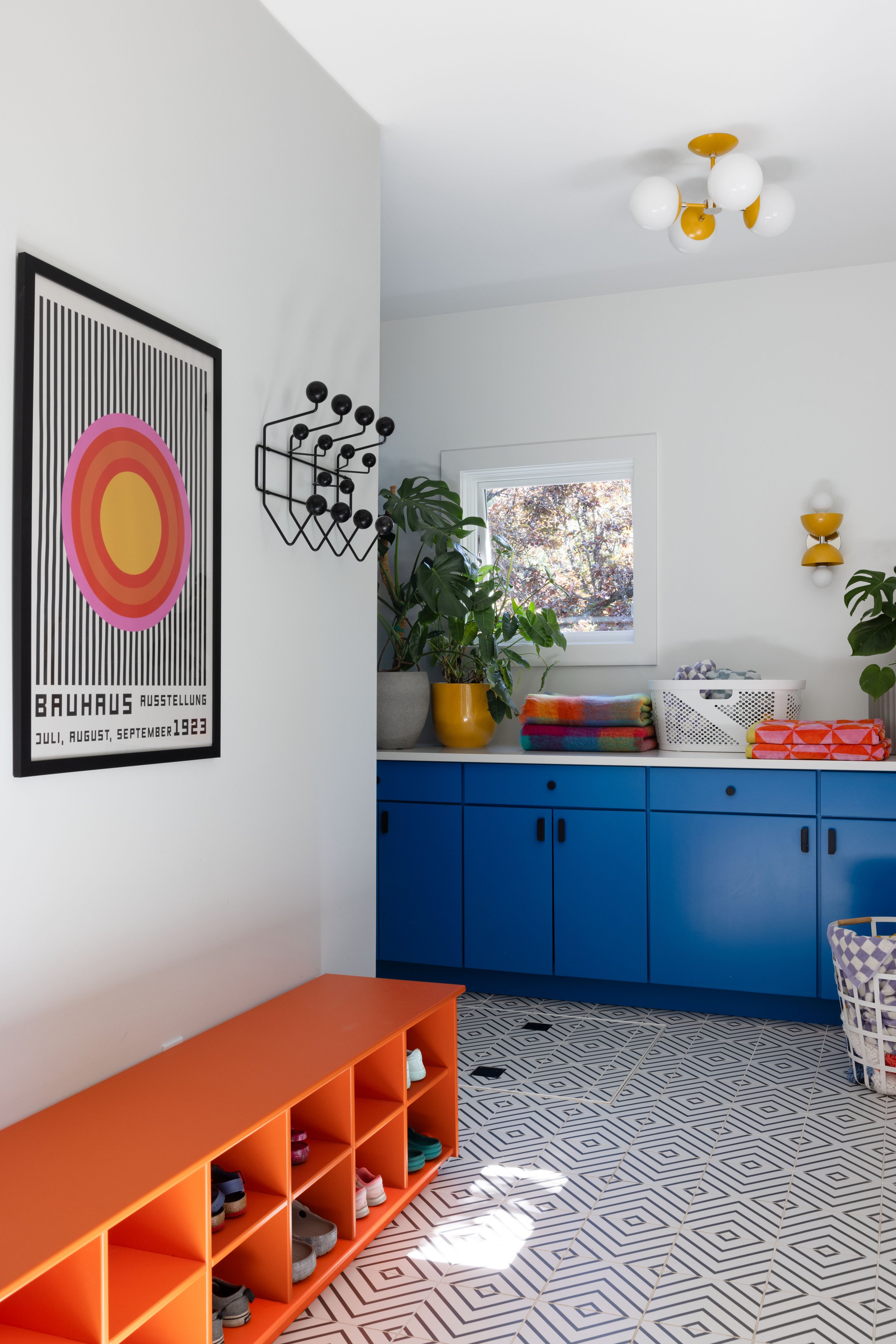 Mudroom with orange shoe storage and cobalt cabinetry.