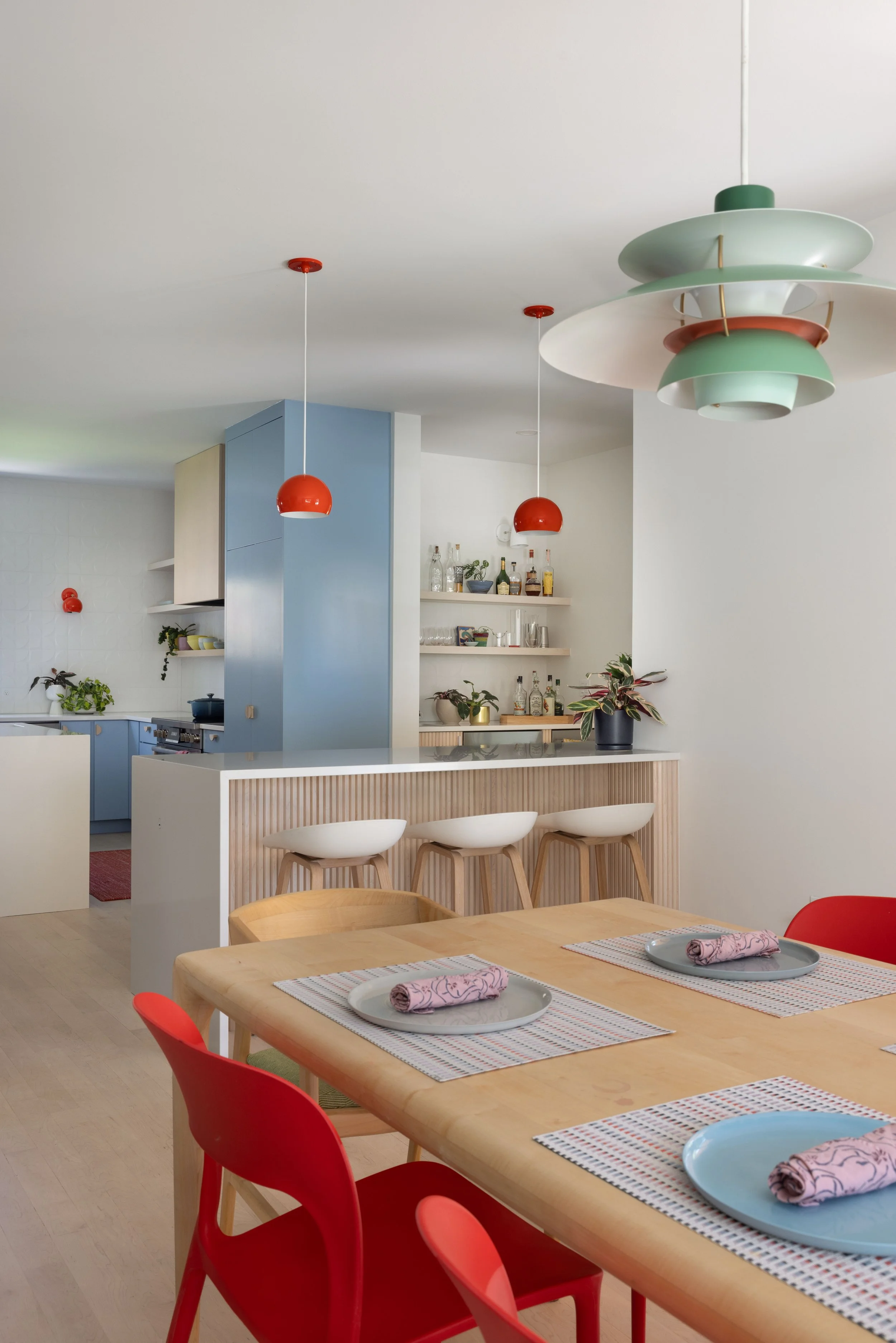 Dining table and red chairs beside the blue kitchen cabinetry.