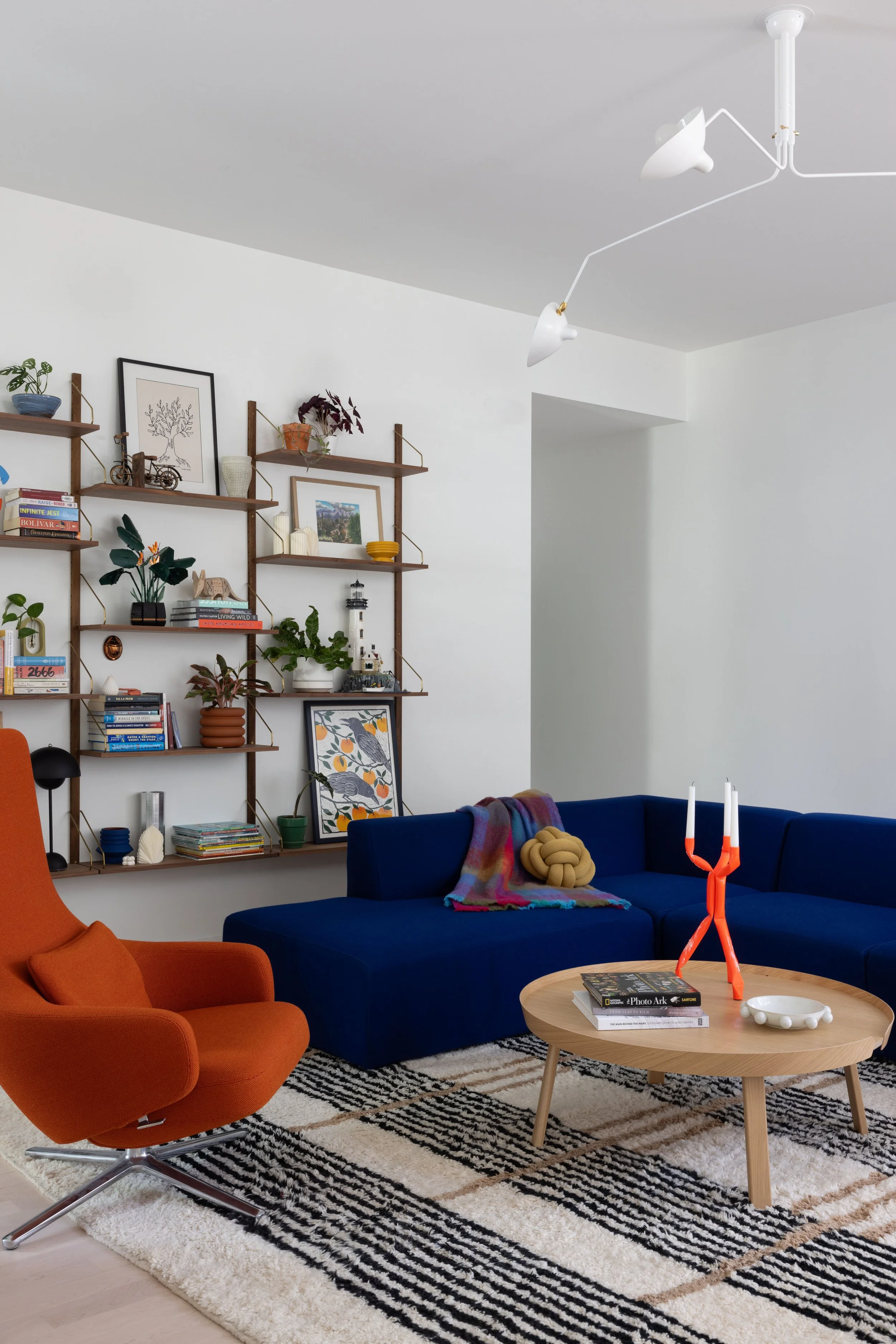 Blue sofa and orange lounge chair beside a round wood coffee table.