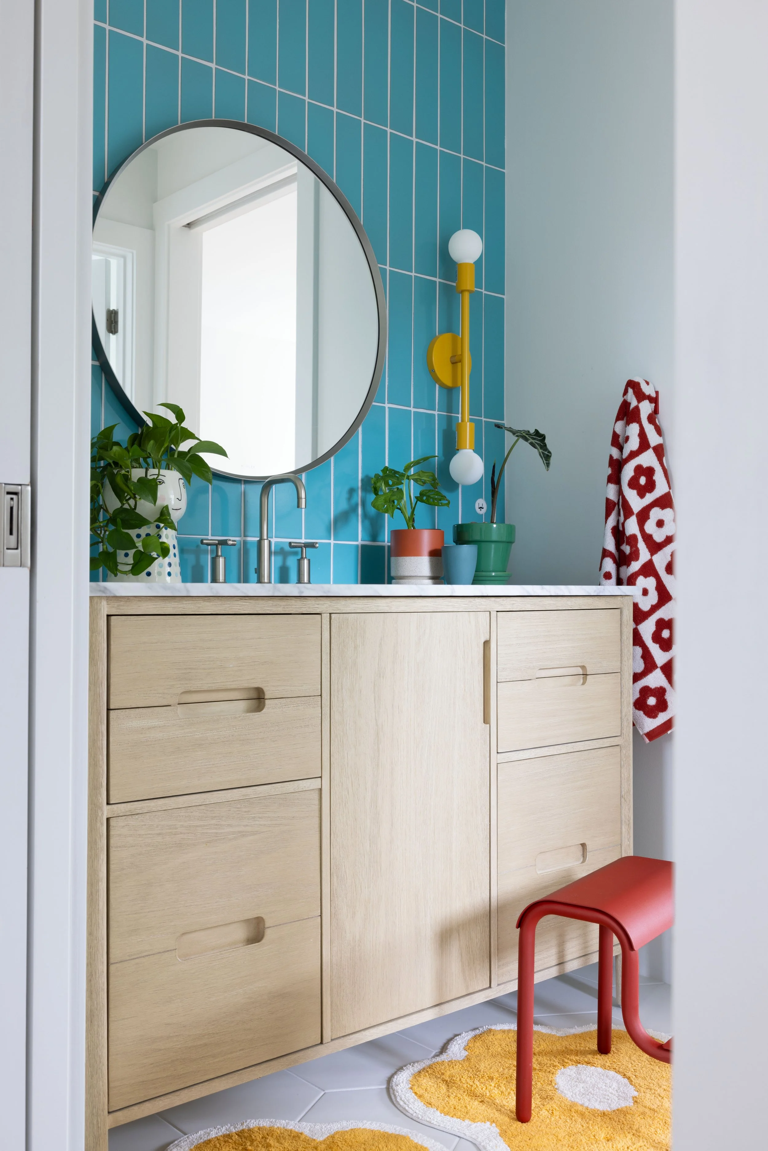 Child’s bathroom with turquoise tile and a round mirror.