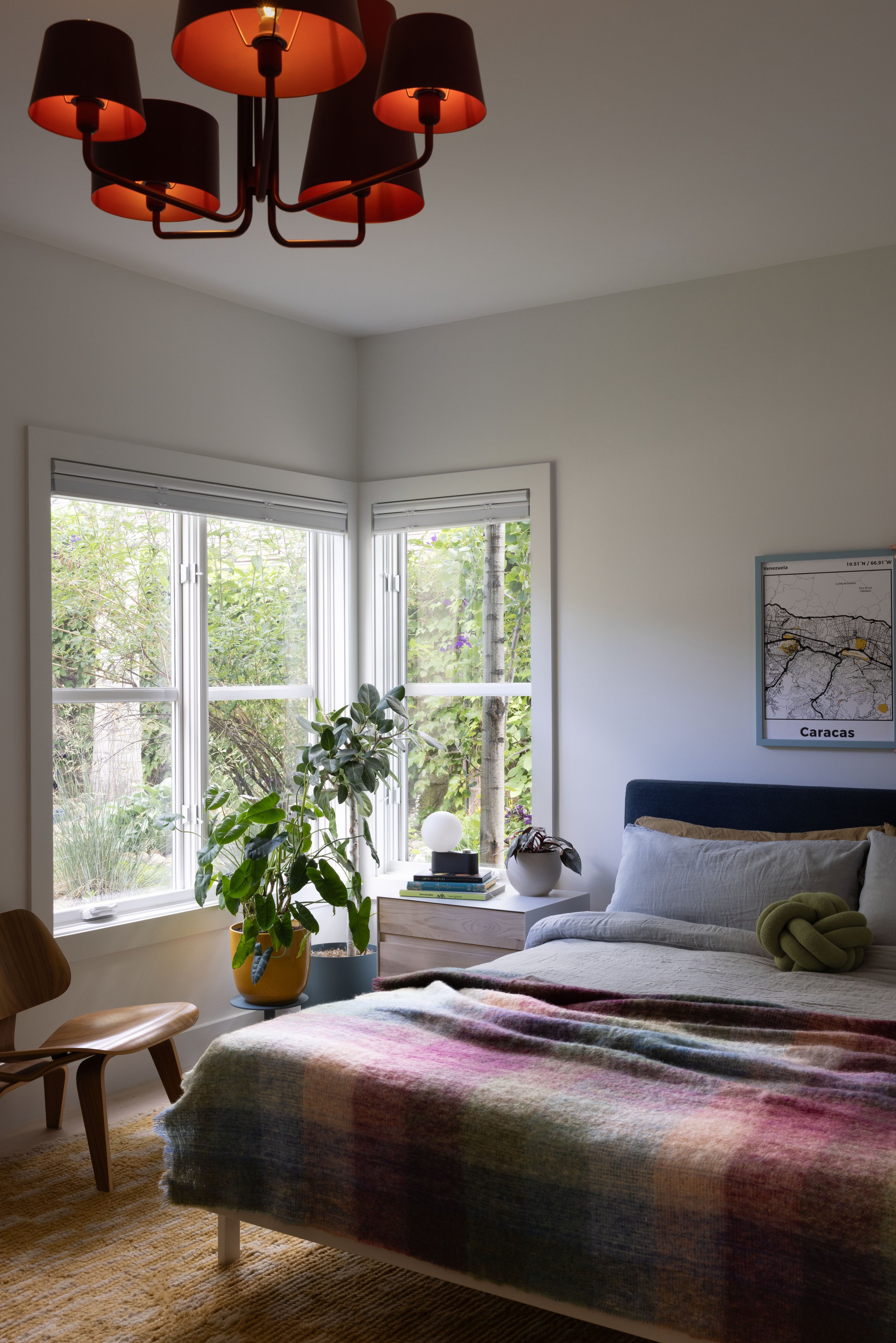 Bedroom with patterned bedding and a sculptural red ceiling light.