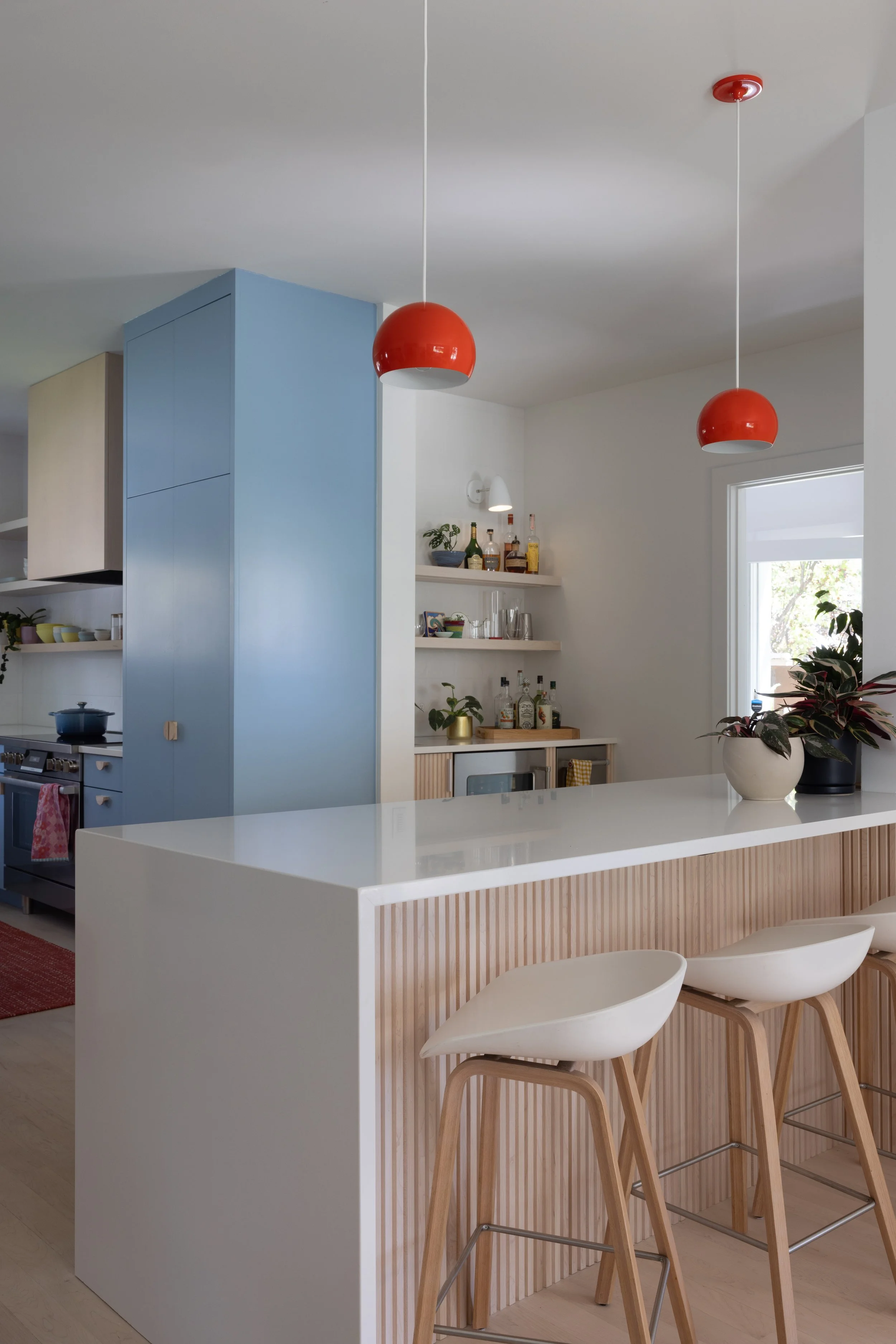 Fluted wood kitchen island beneath red pendant lights.