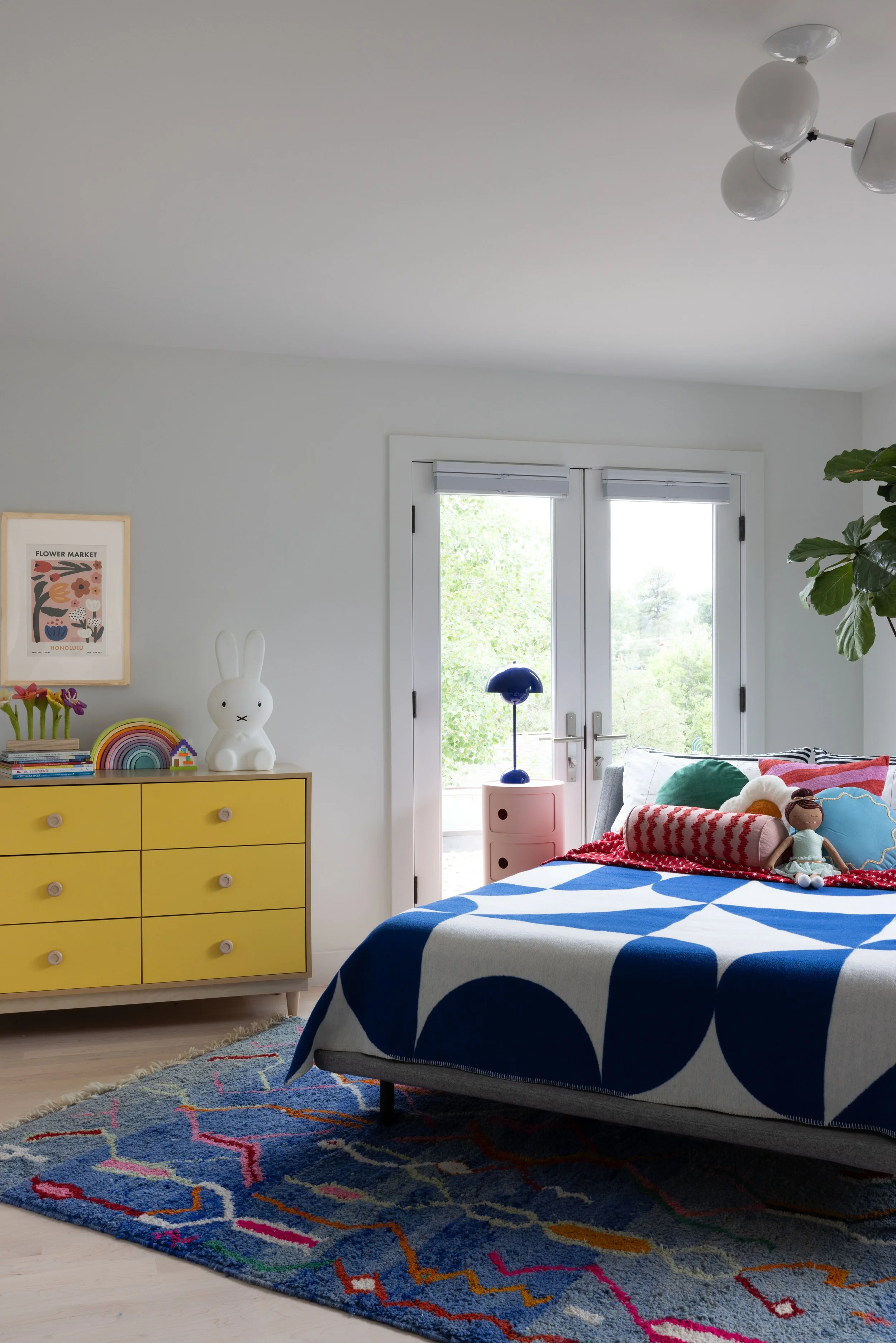 Bedroom with a patterned bedspread and mustard dresser.