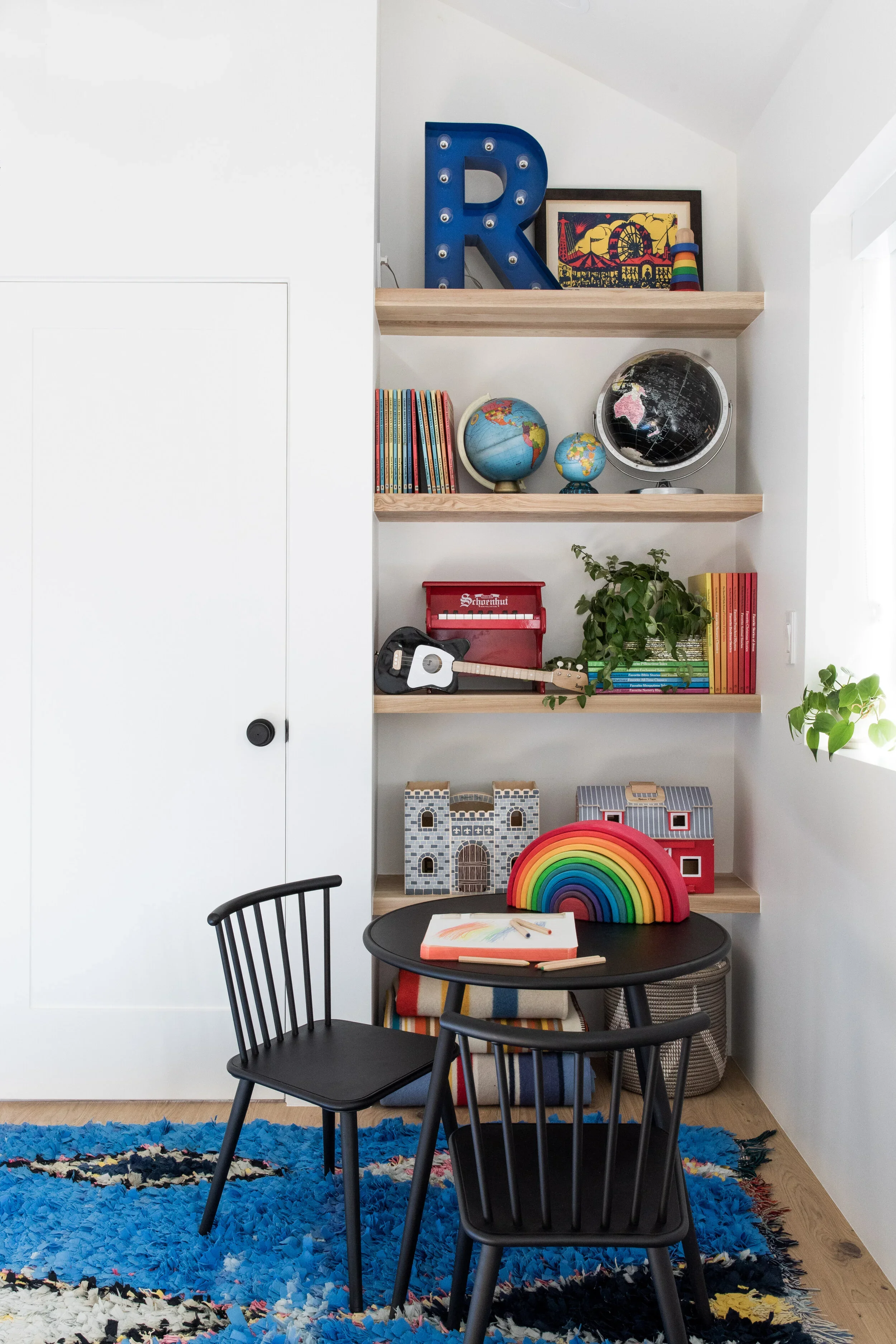 Built-in shelving with colorful glassware and a small dining table.