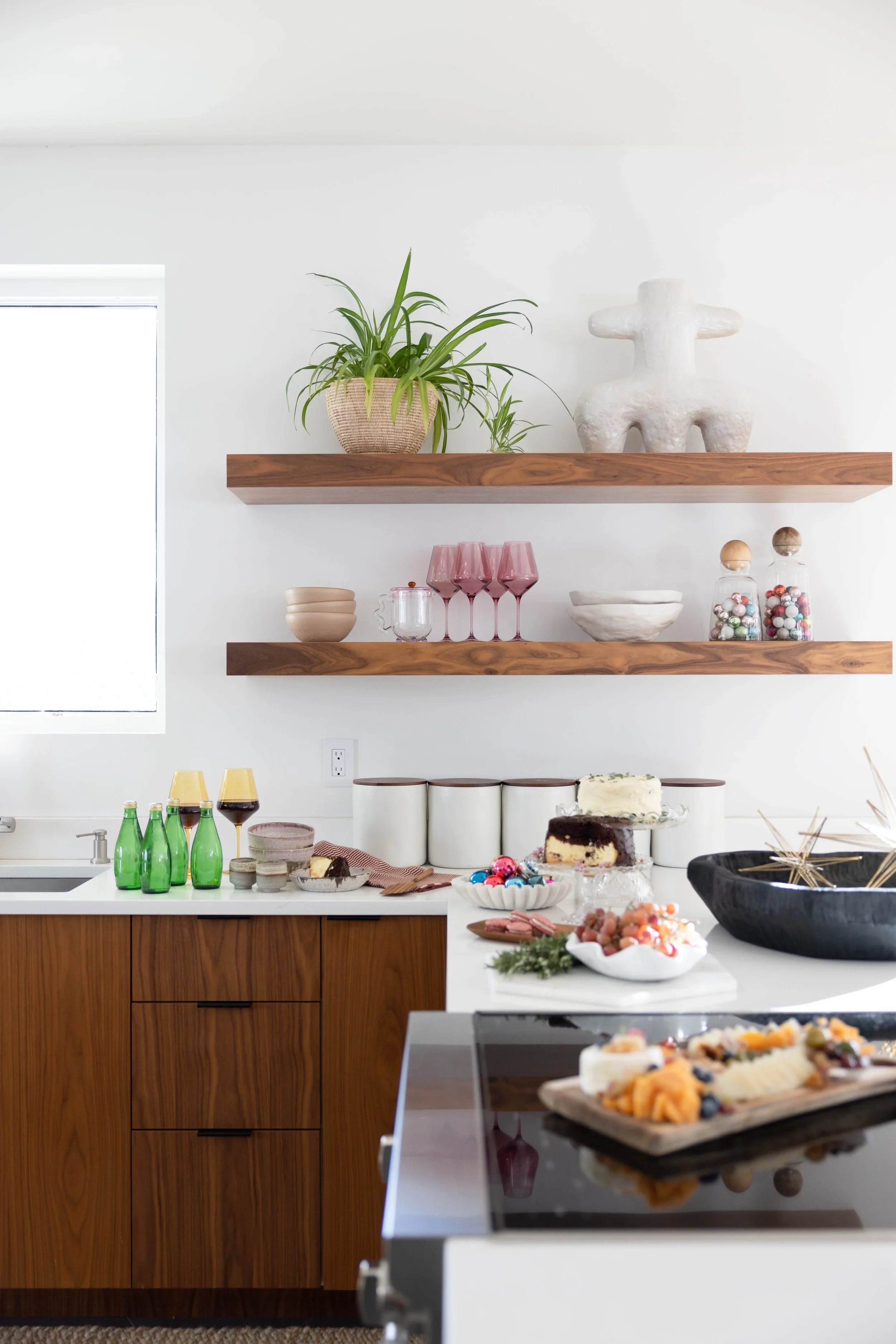 Walnut kitchen cabinets with open shelves and potted plants.