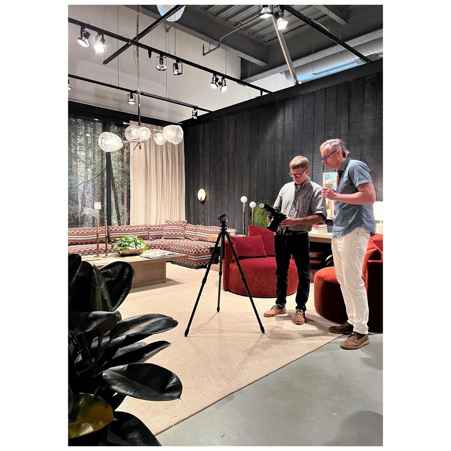 Designers discussing the completed showroom beside filming equipment