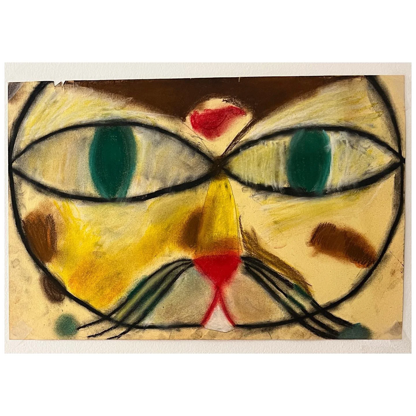 Colorful painted cat face with green eyes on textured paper