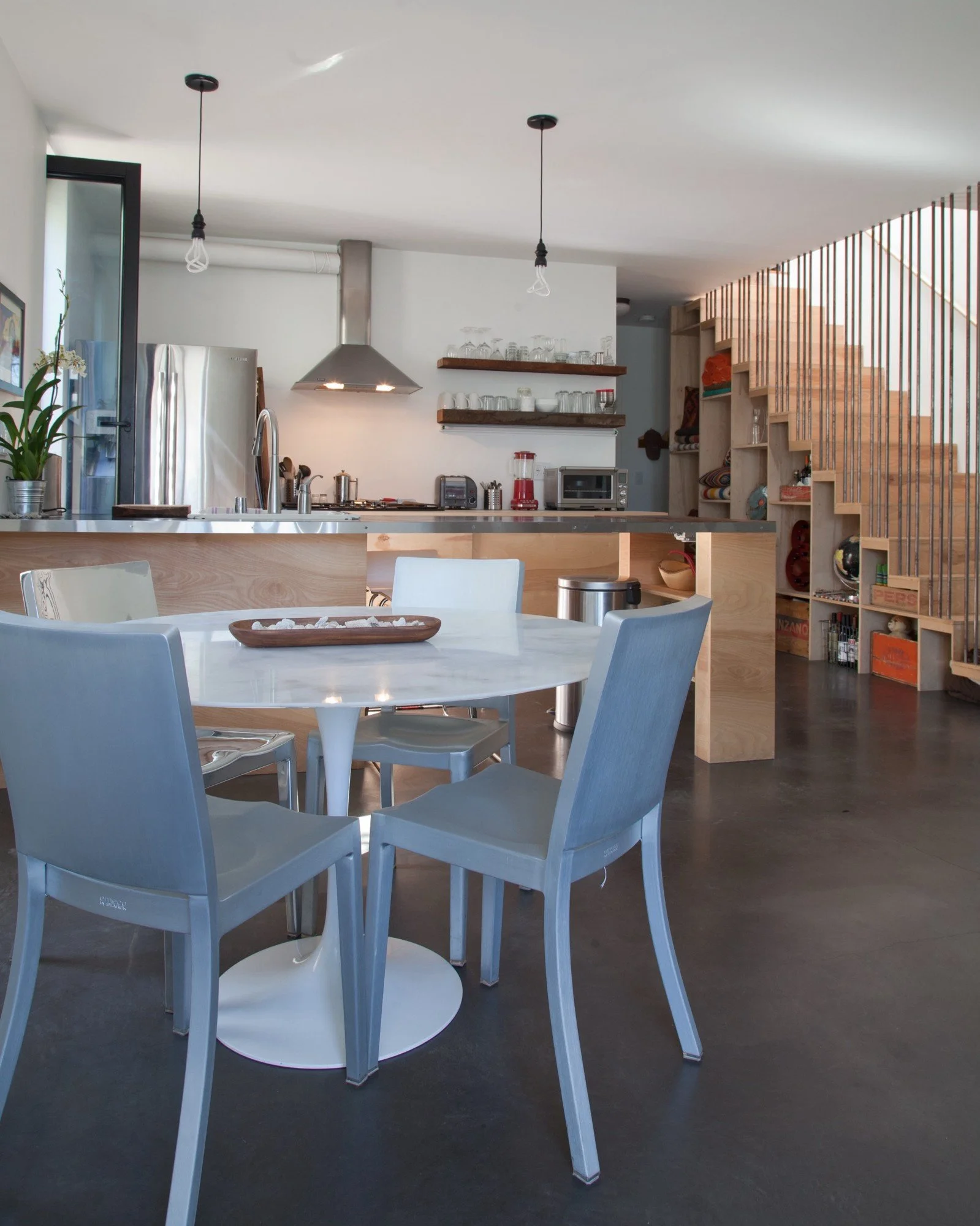 White dining table and blue chairs beside an open kitchen
