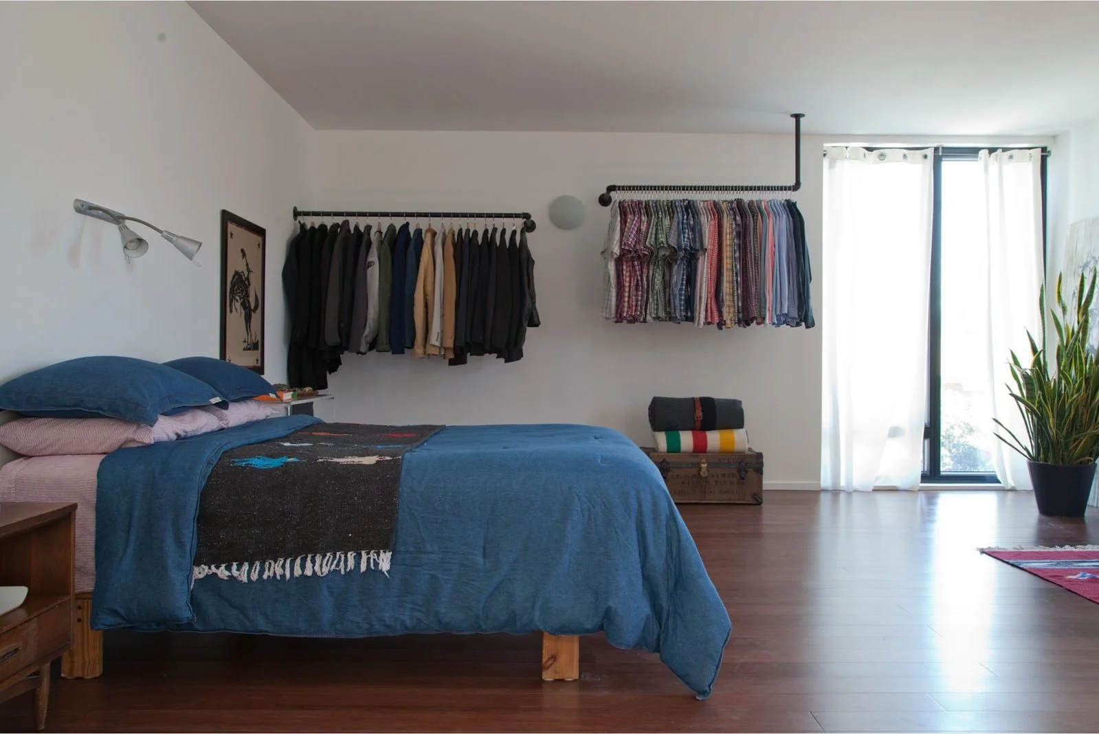 Bedroom with blue bedding, white walls and open clothes rails