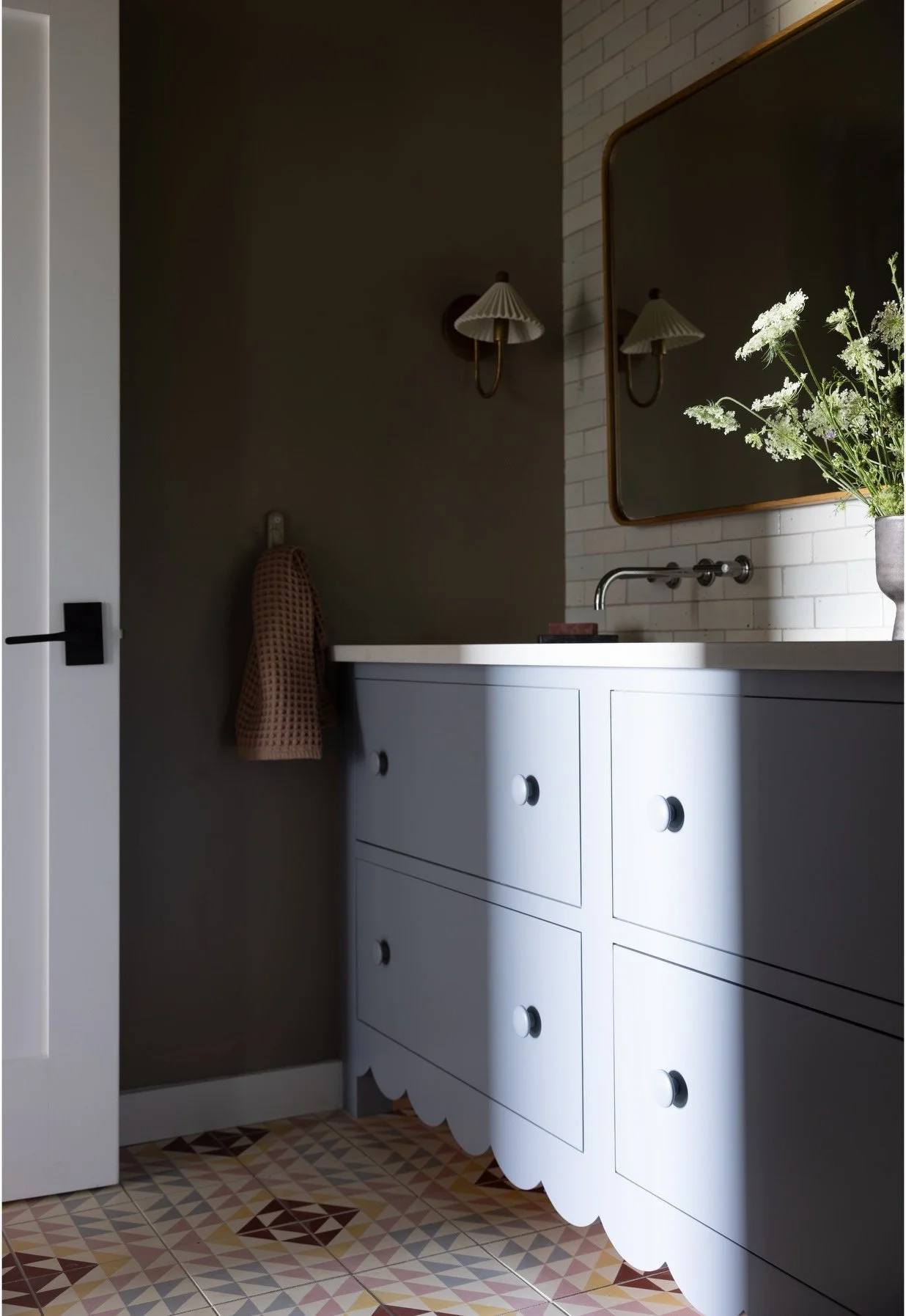 Blue-gray vanity against dark walls with brass fittings