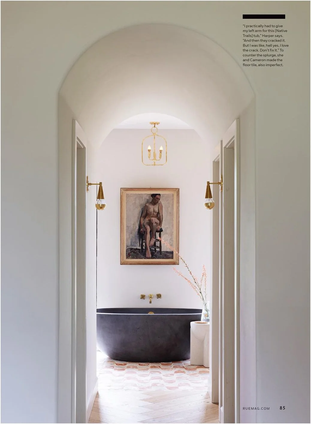 Arched bathroom doorway framing a freestanding bathtub and artwork