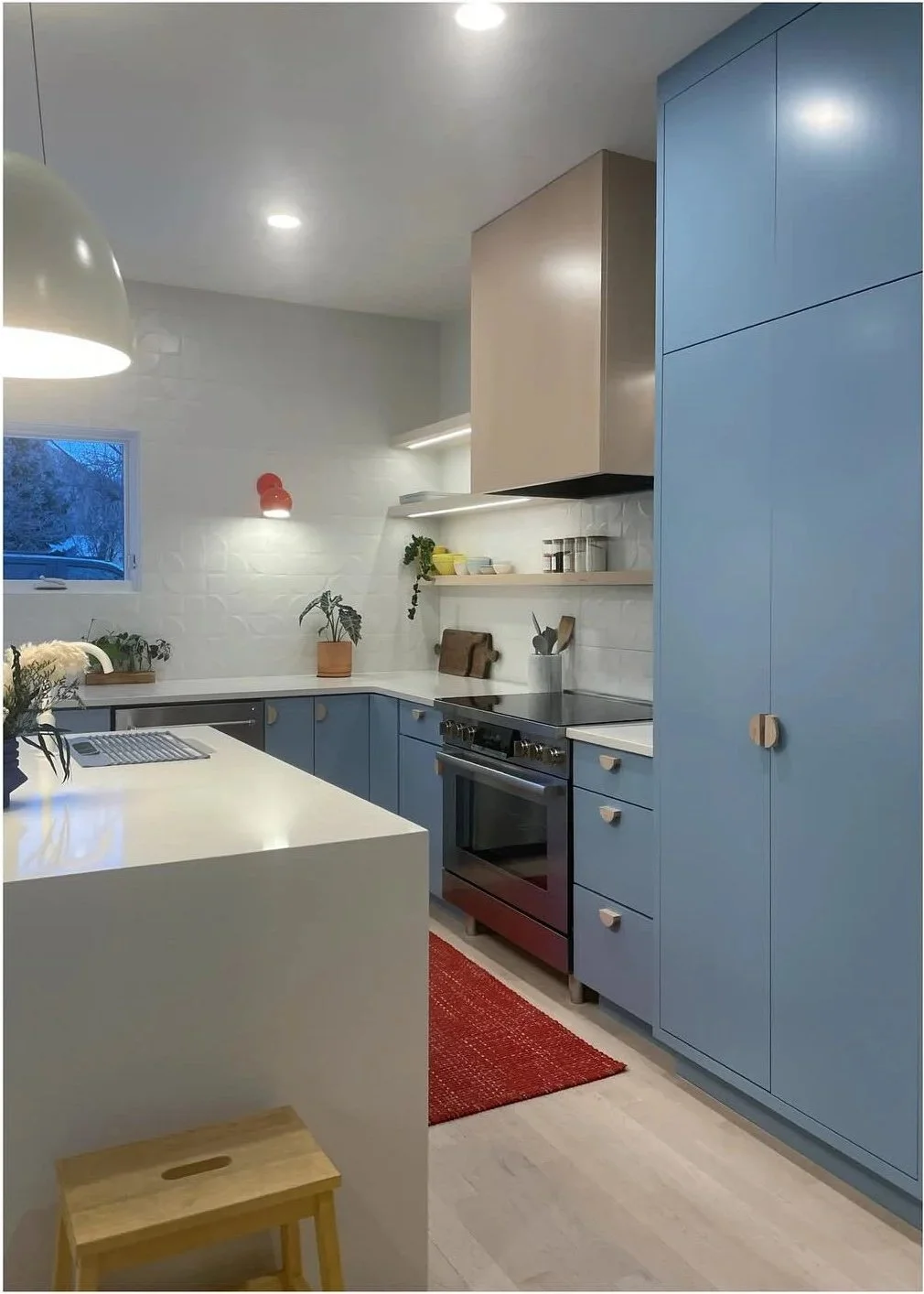 Blue full-height cabinets beside a light kitchen island