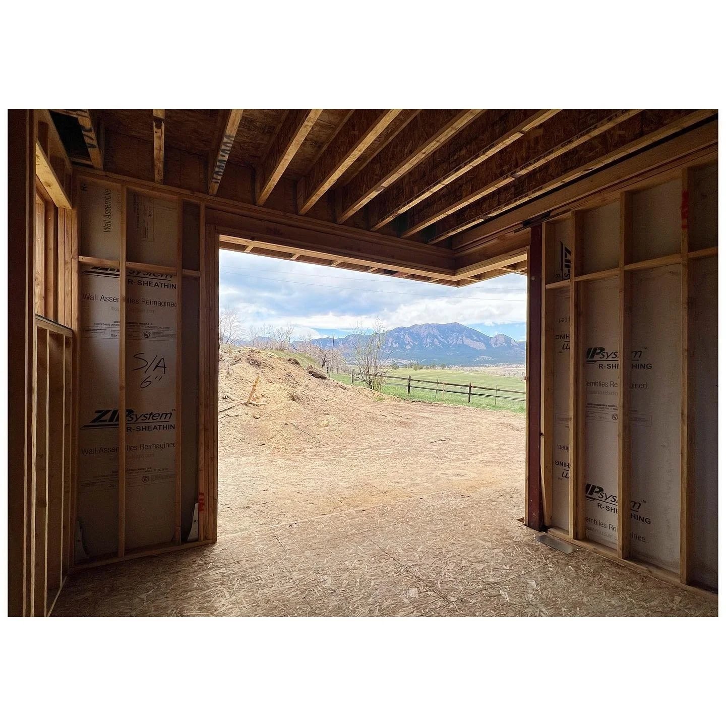 Unfinished timber-framed room opening toward a broad landscape and distant hills