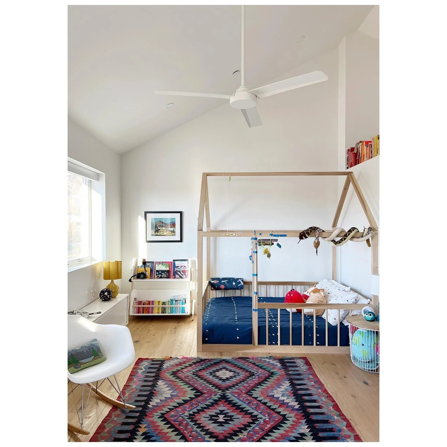 Bedroom with a timber house-frame bed bright rug and open shelving