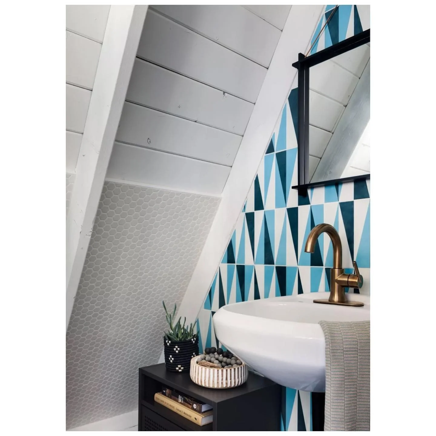 A-frame bathroom with blue geometric tile a white basin and brass tap