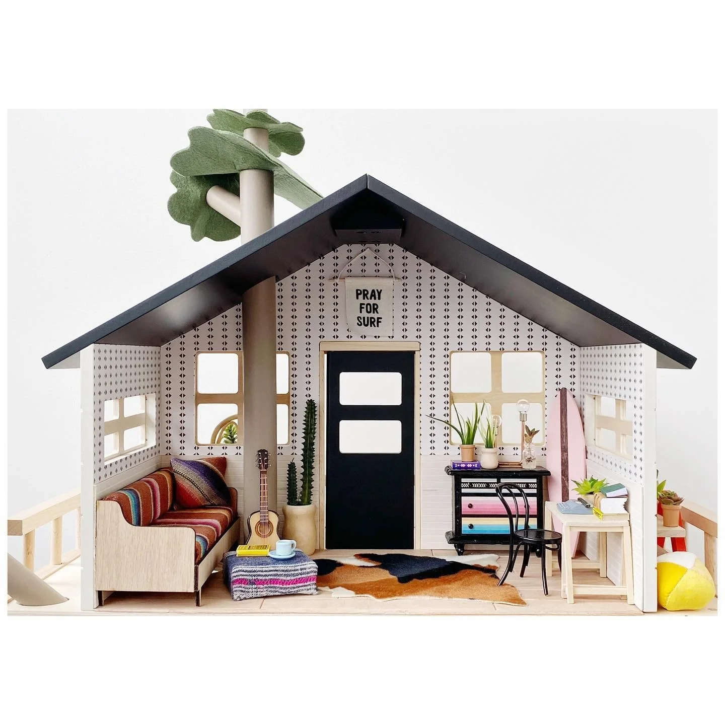 Open-front dollhouse with pale rooms miniature furnishings a dark roof and a green door