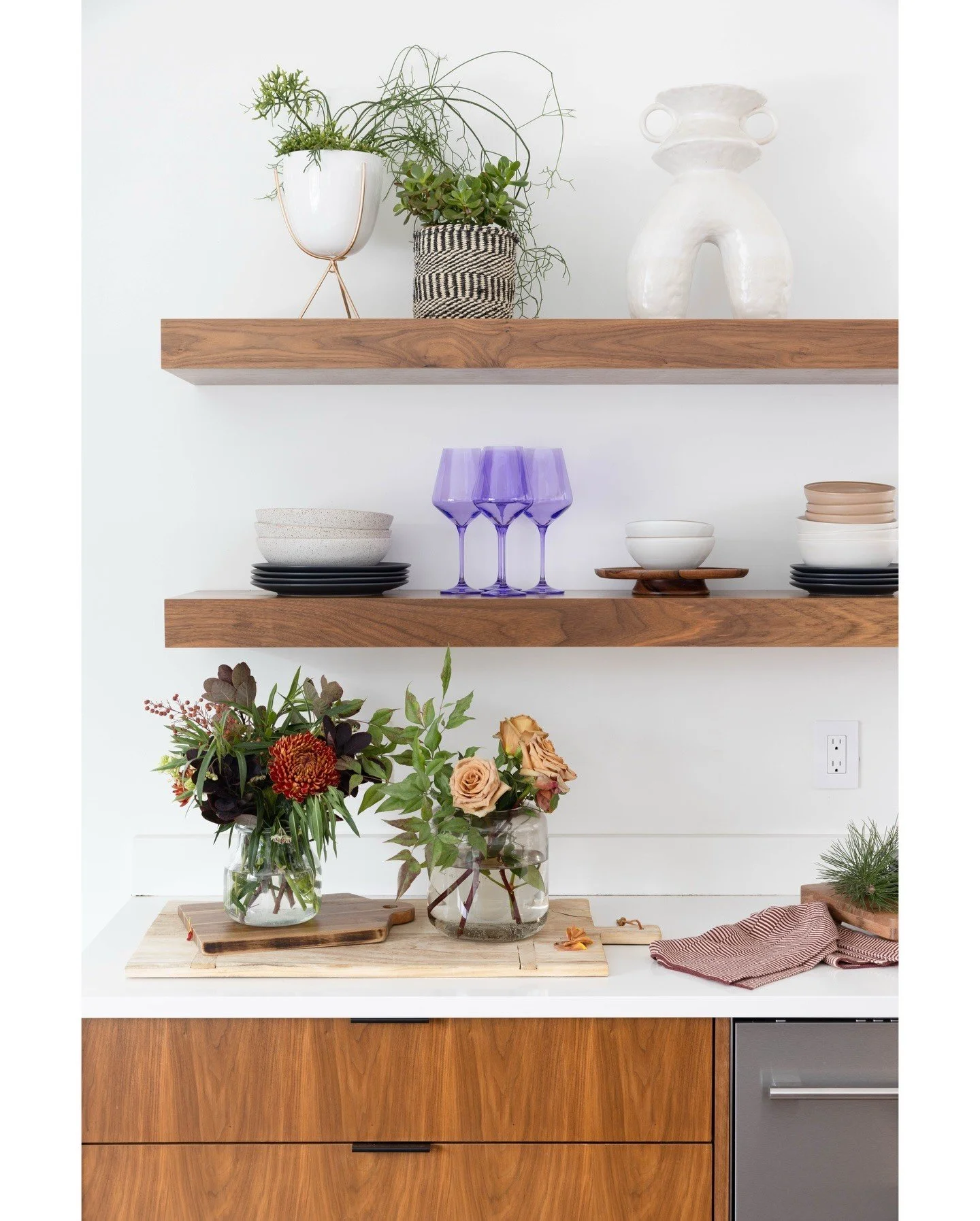 Open kitchen shelves with plants small pottery and purple glassware