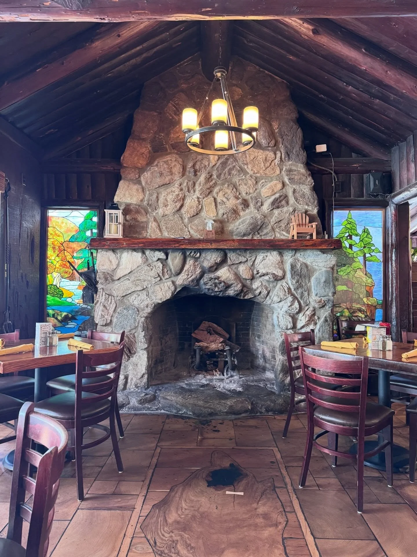 Large stone fireplace beneath timber roof beams in a rustic dining room