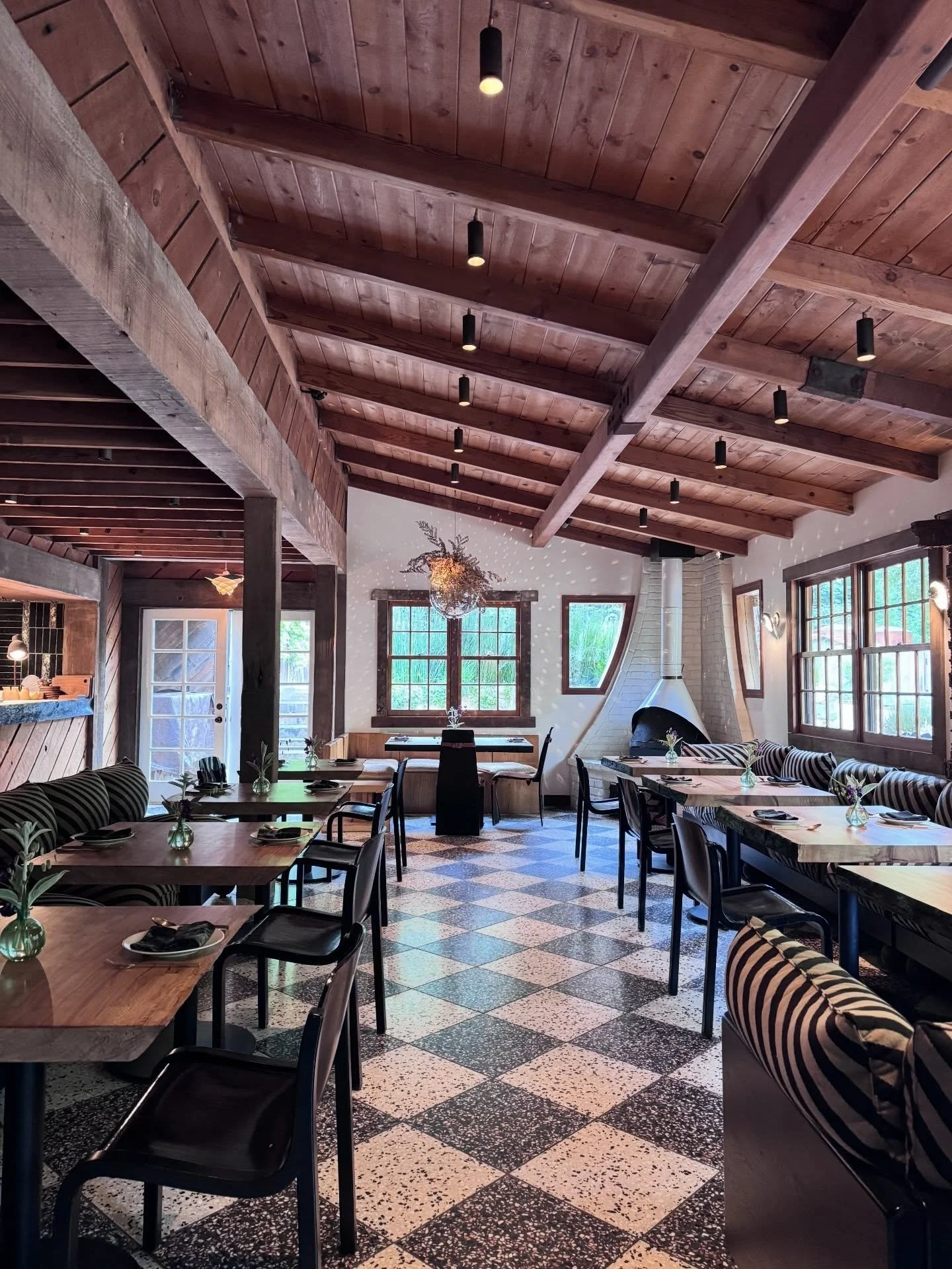 Restaurant dining room with exposed timber beams checked floor tiles and broad windows