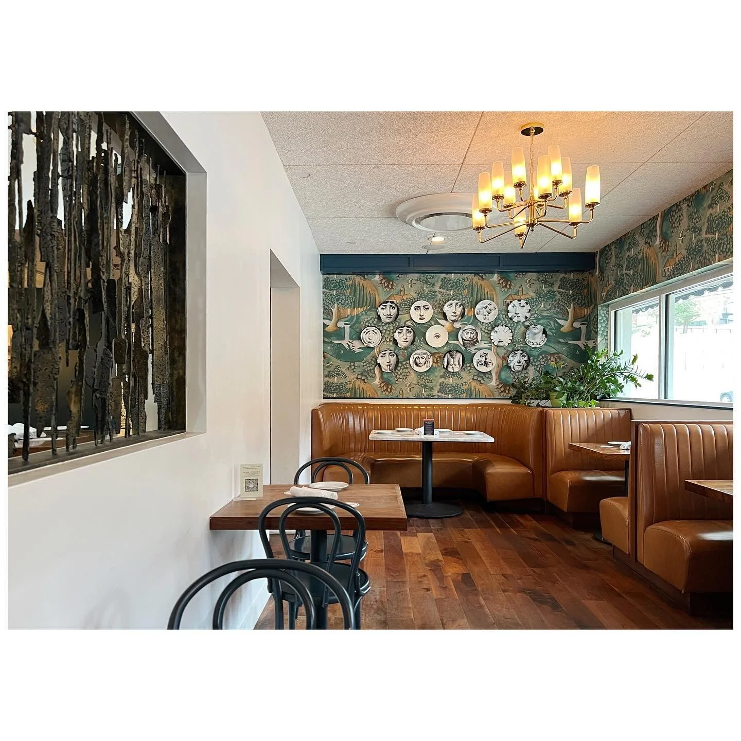 Caramel leather restaurant booths with Fornasetti plates and black bentwood chairs