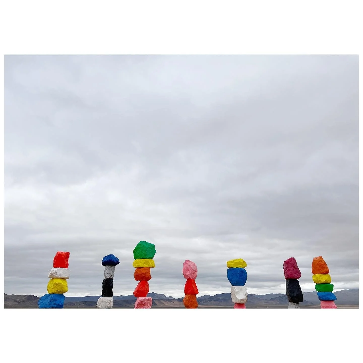 Seven columns of colorful painted boulders arranged across the desert